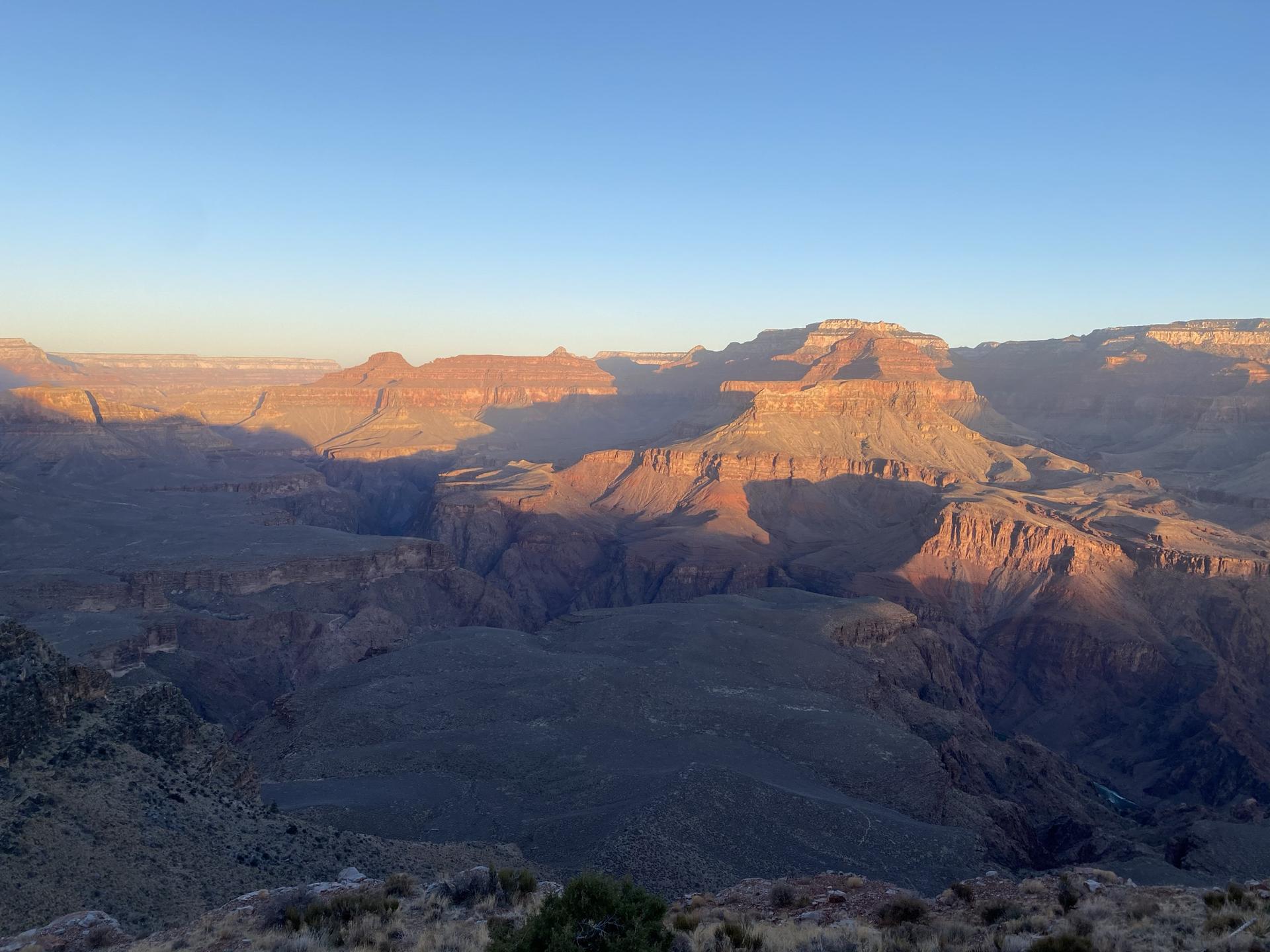 Wide canyon landscape at golden hour, with long shadows across mesas.