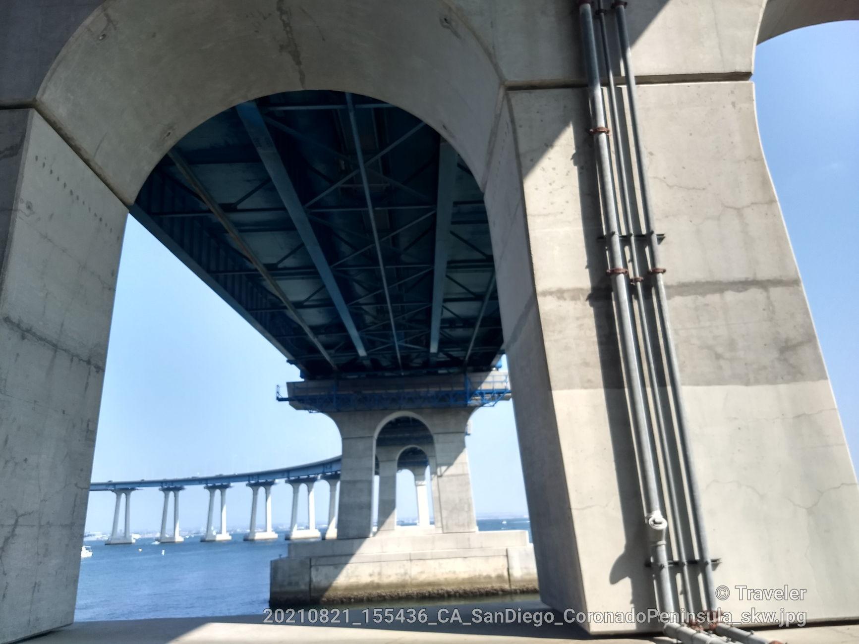 View from under a large concrete bridge archway towards distant spans.