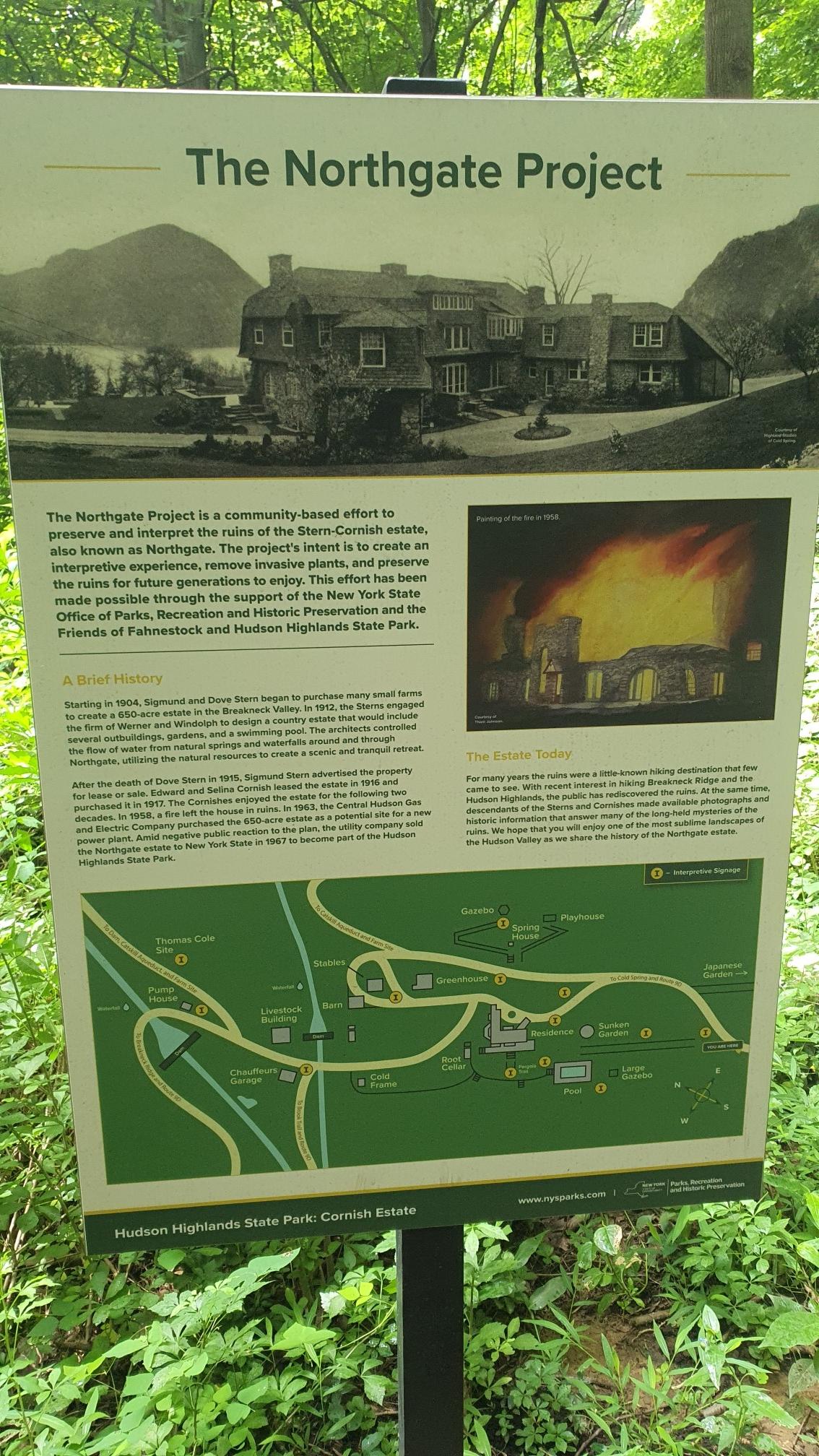 Informational sign about a historical project with text and images in a forest.