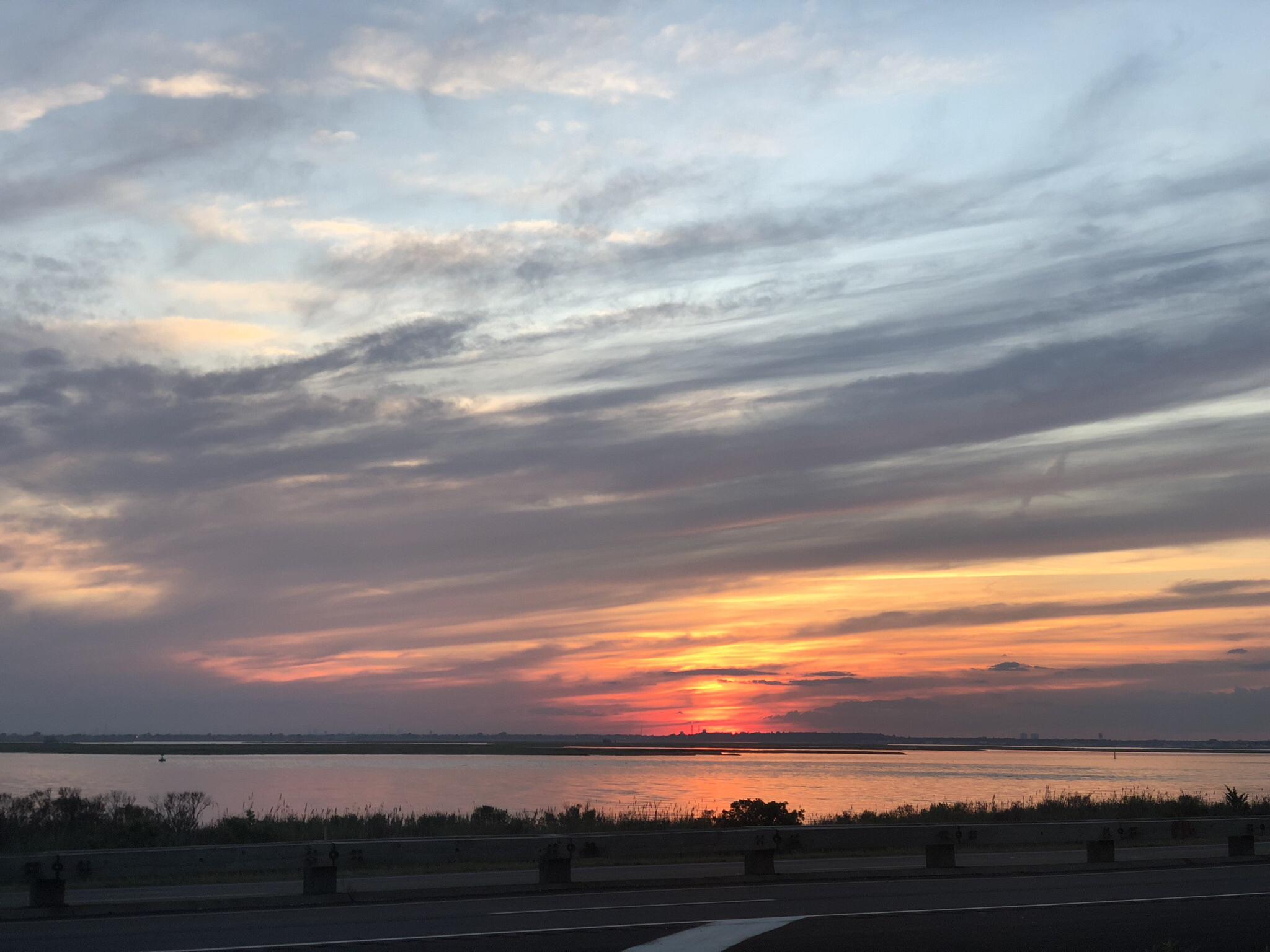 Vibrant sunset with orange and pink clouds over a calm body of water.