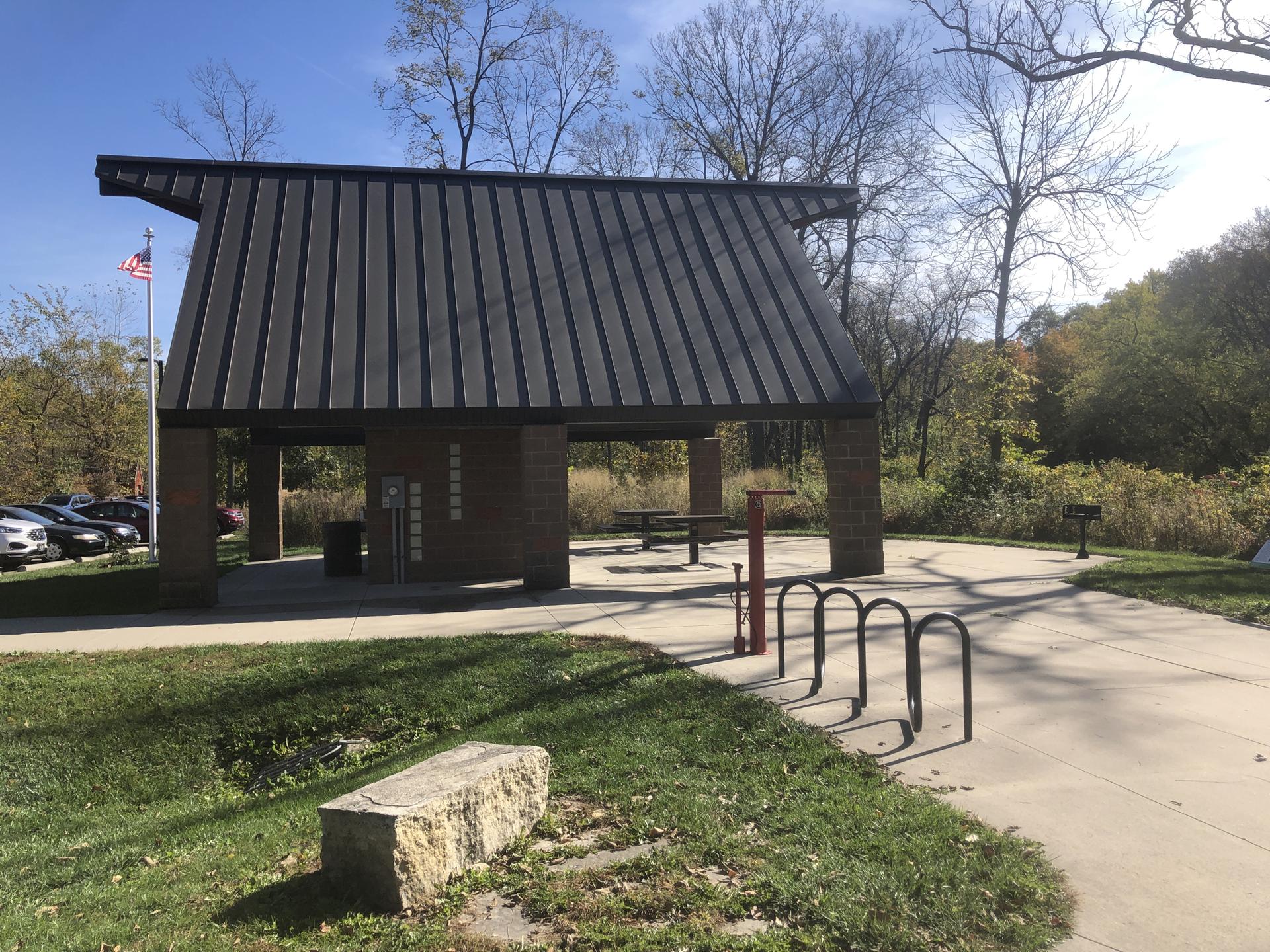 A large picnic shelter with a dark roof on a sunny day.