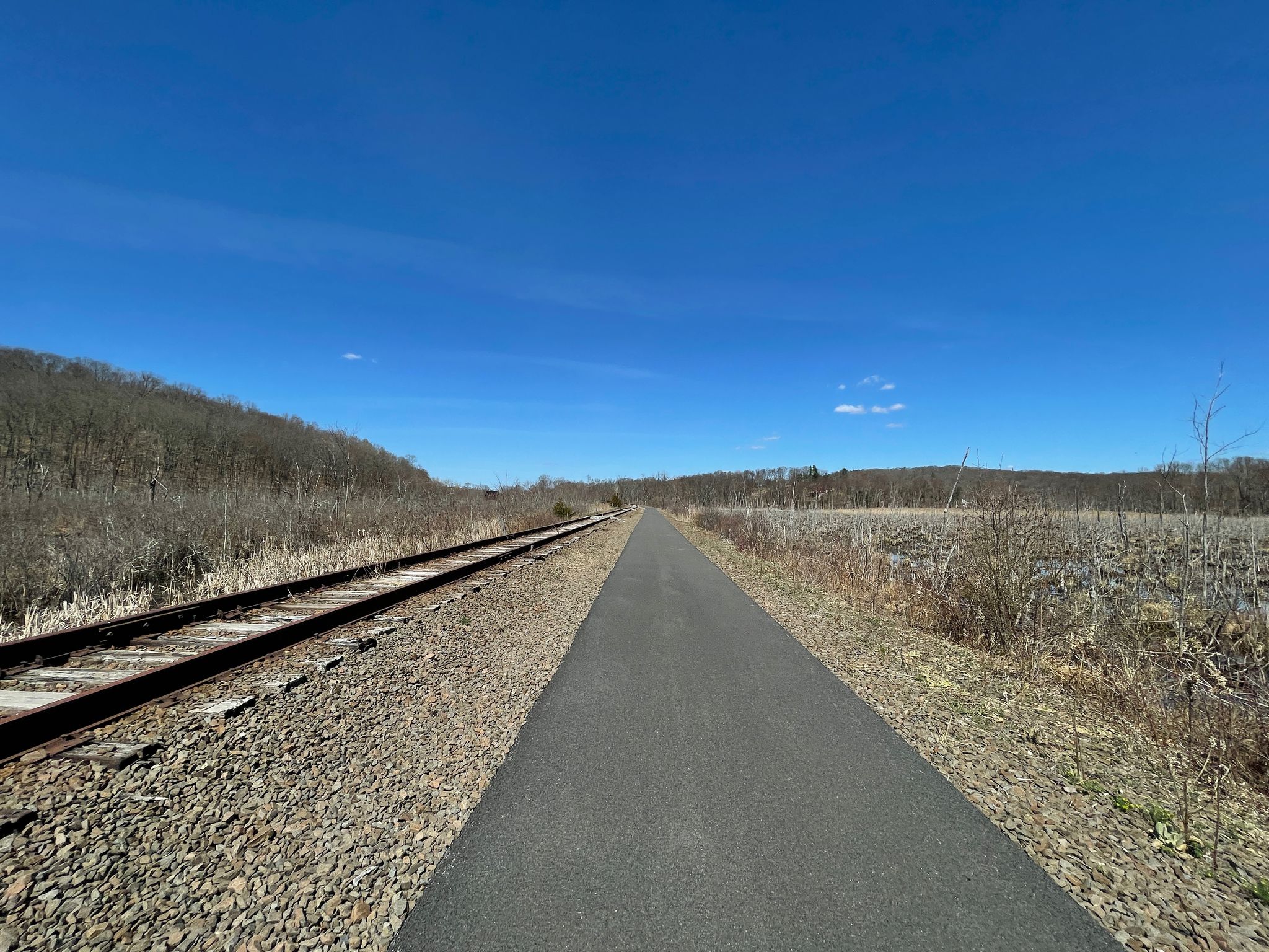 Paved path next to railroad tracks under a clear blue sky. - Lake Carmel Loop