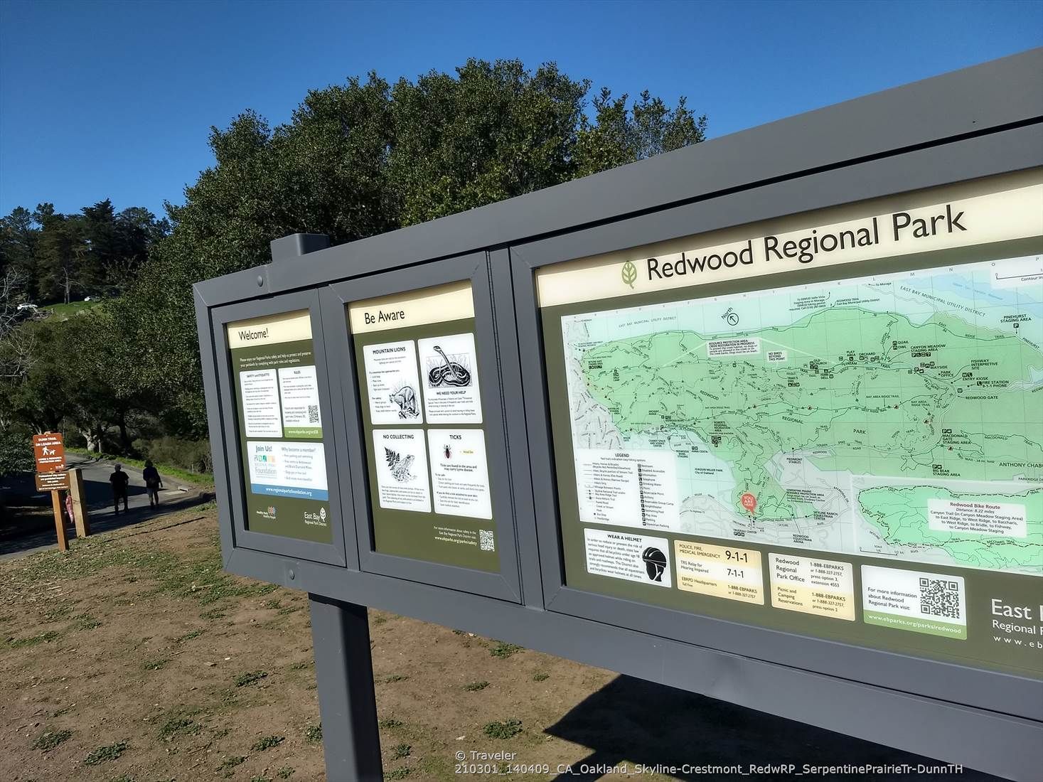 A large park information sign with maps and warnings under a clear sky. - Dunn Trail