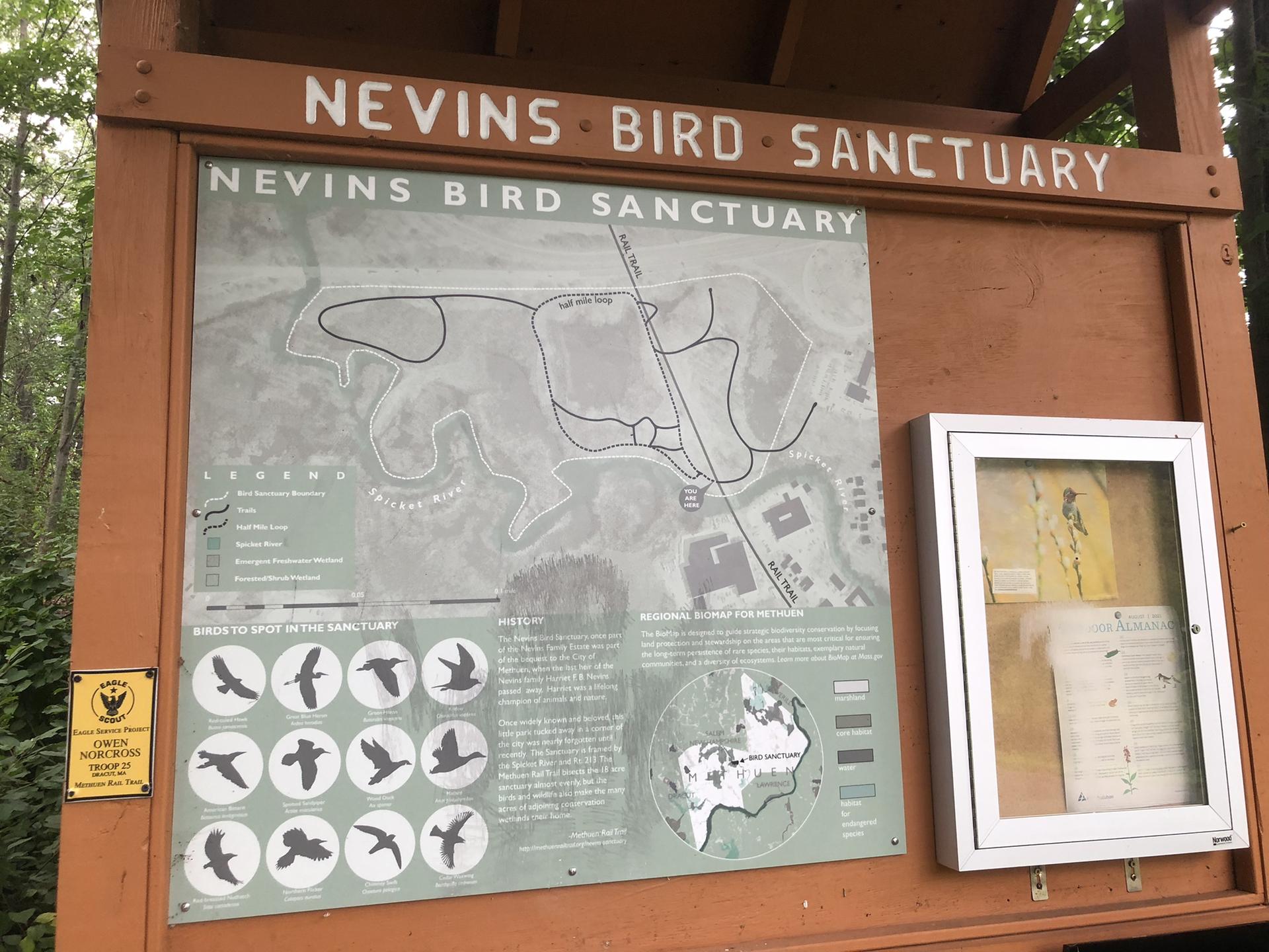 Wooden information board displaying a trail map and bird silhouettes.