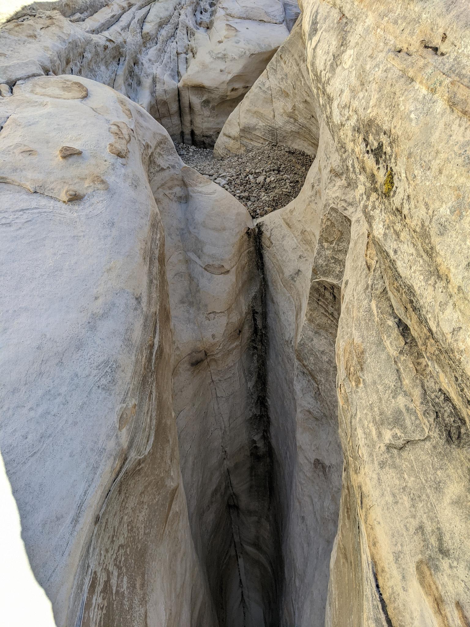 Narrow, deep slot canyon with light-colored, textured rock walls.
