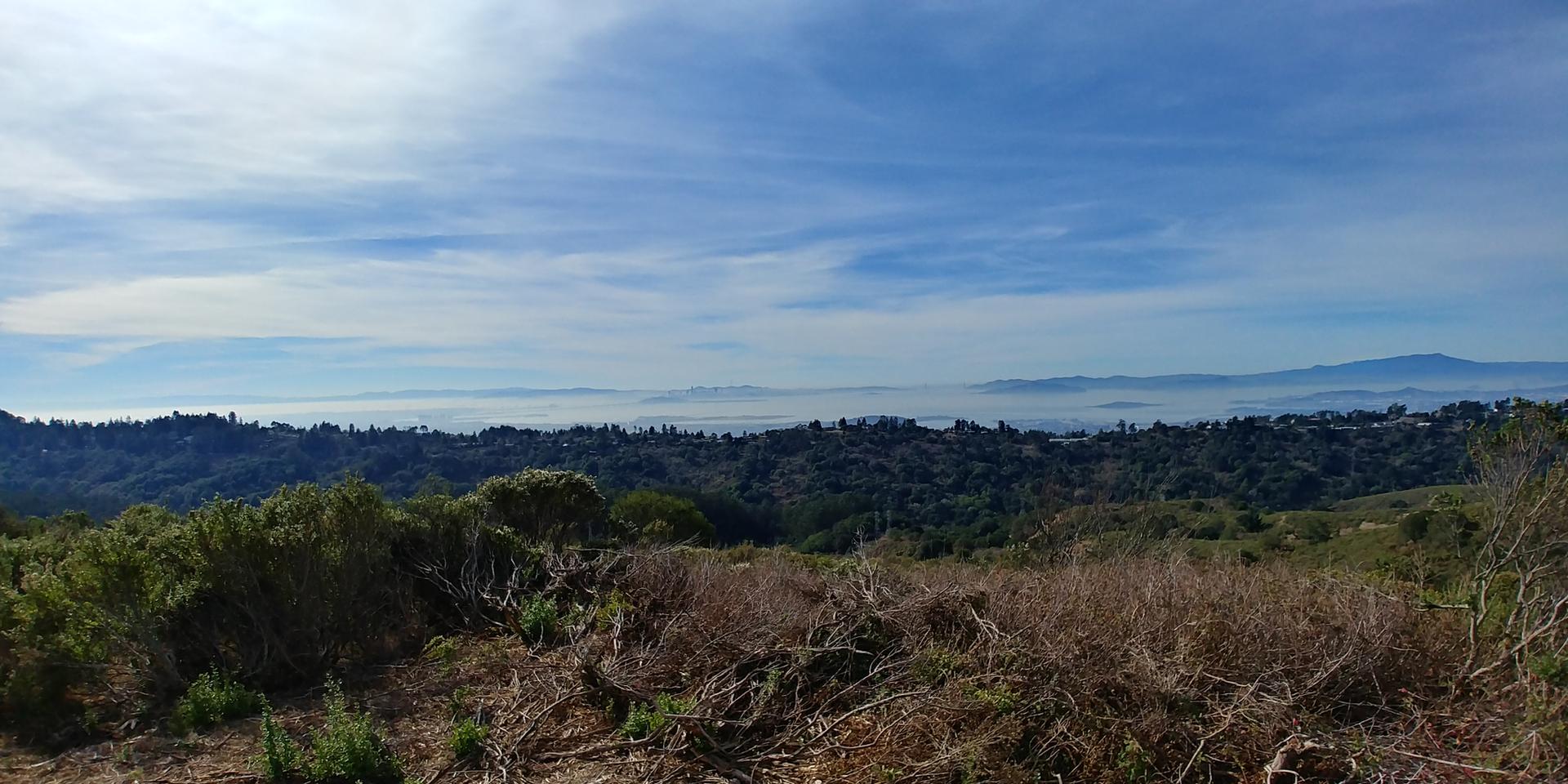 Panoramic view of rolling green hills, a misty valley, and distant mountains.