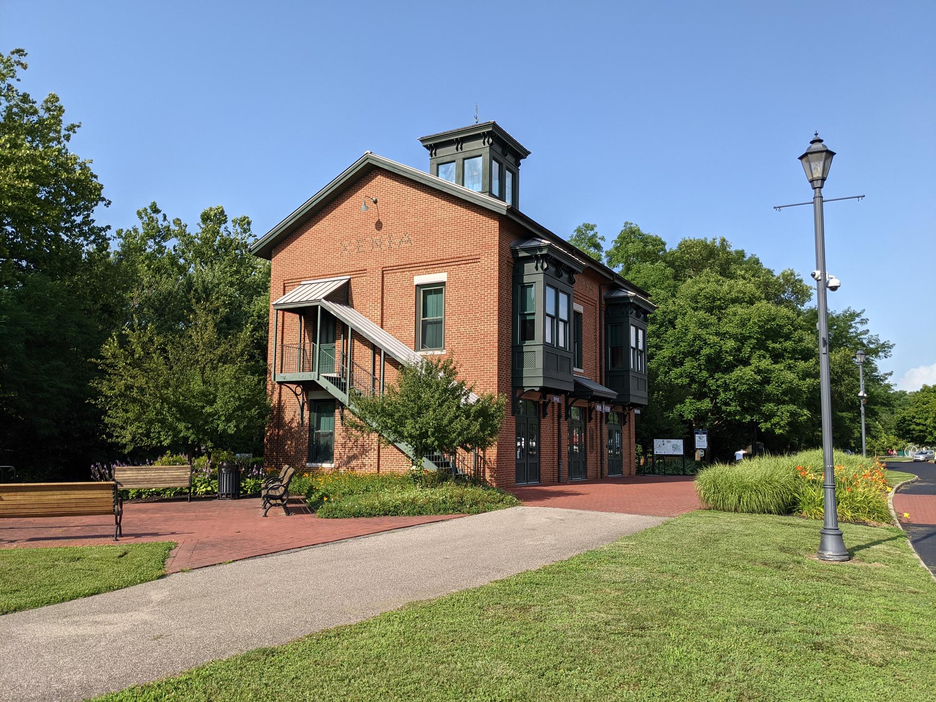 Red brick building with a tower, green grass, and clear sky.