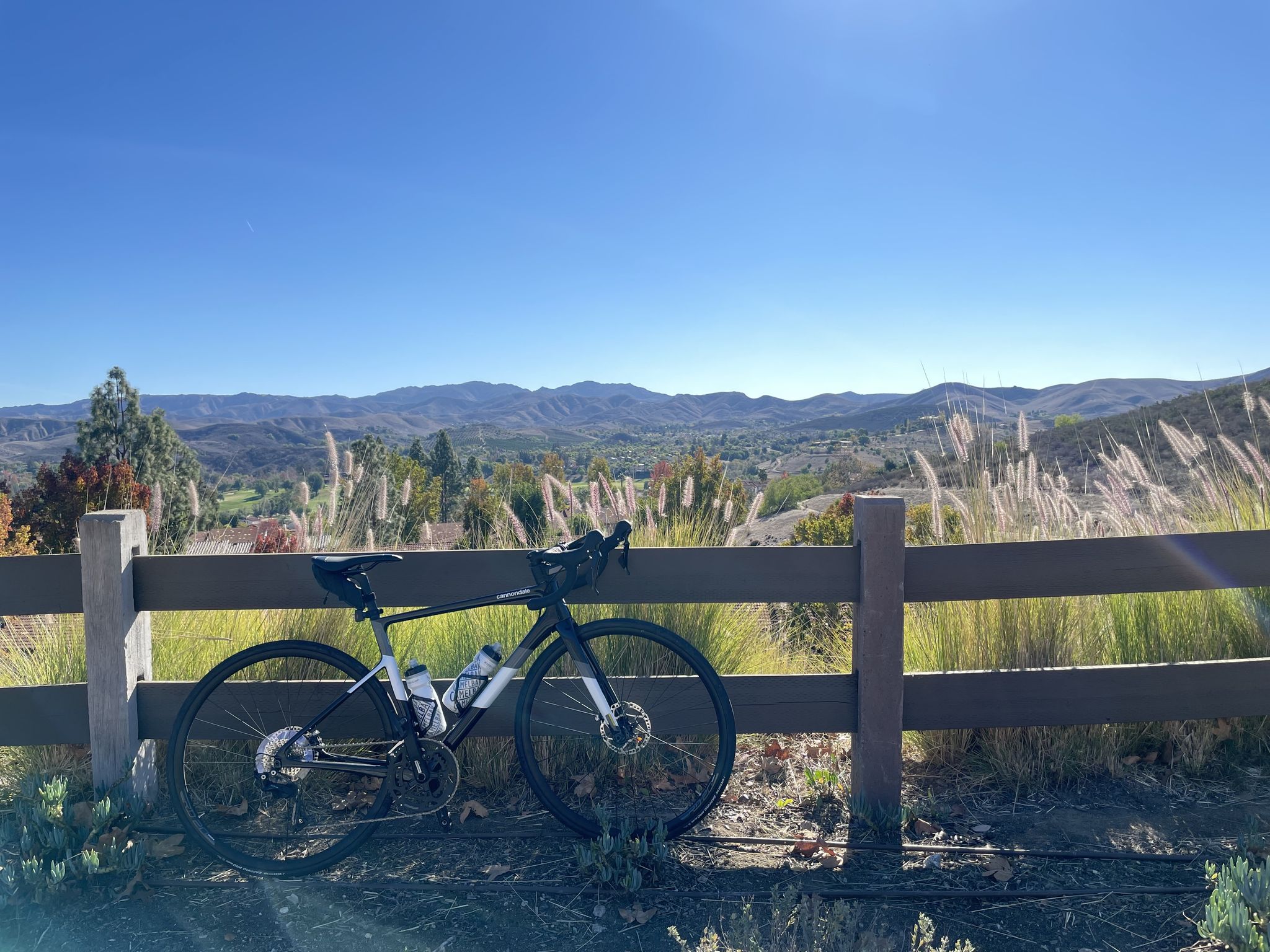 A bicycle leans on a fence overlooking sunny mountains and grassy hills. - Sunset Hills Open Space – Colorful Landscape and Sunny Canyon Views loop from Simi Valley