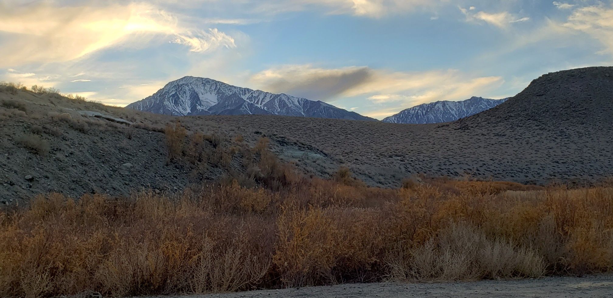 Snow-capped mountains behind dry hills and golden vegetation under a cloudy sky. - Pleasant Valley Dam loop — Gravel