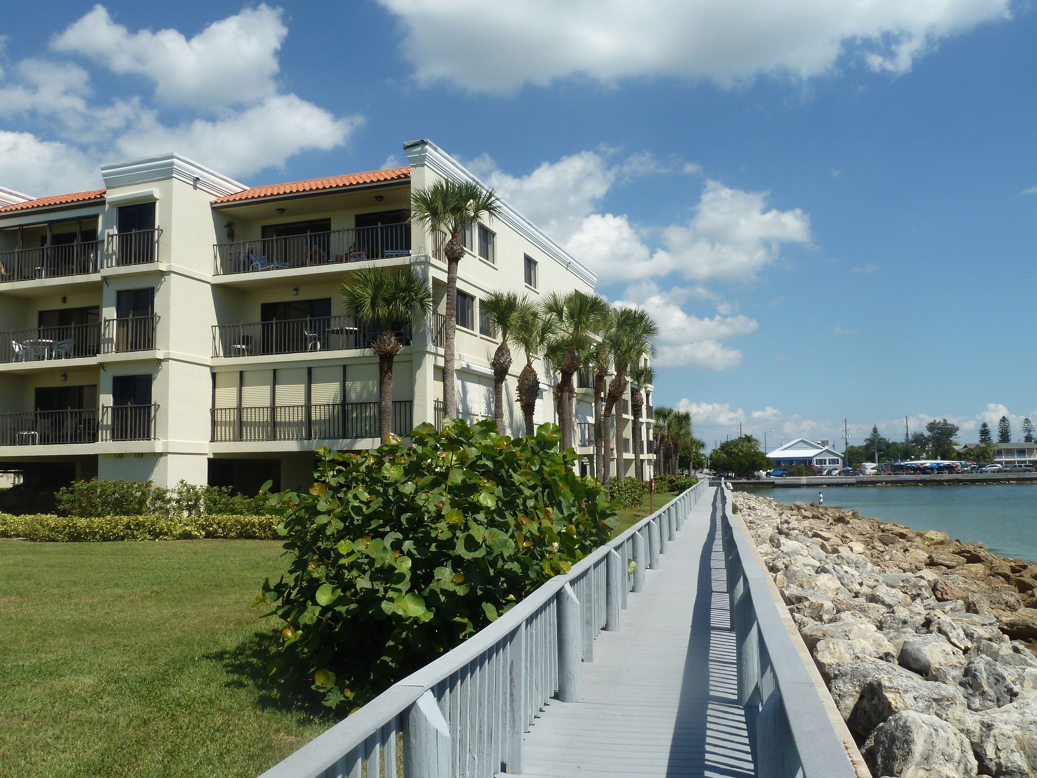 Large building next to a boardwalk along a sunny, rocky coastline. - Sunset Beach Scenic Boardwalk Loop