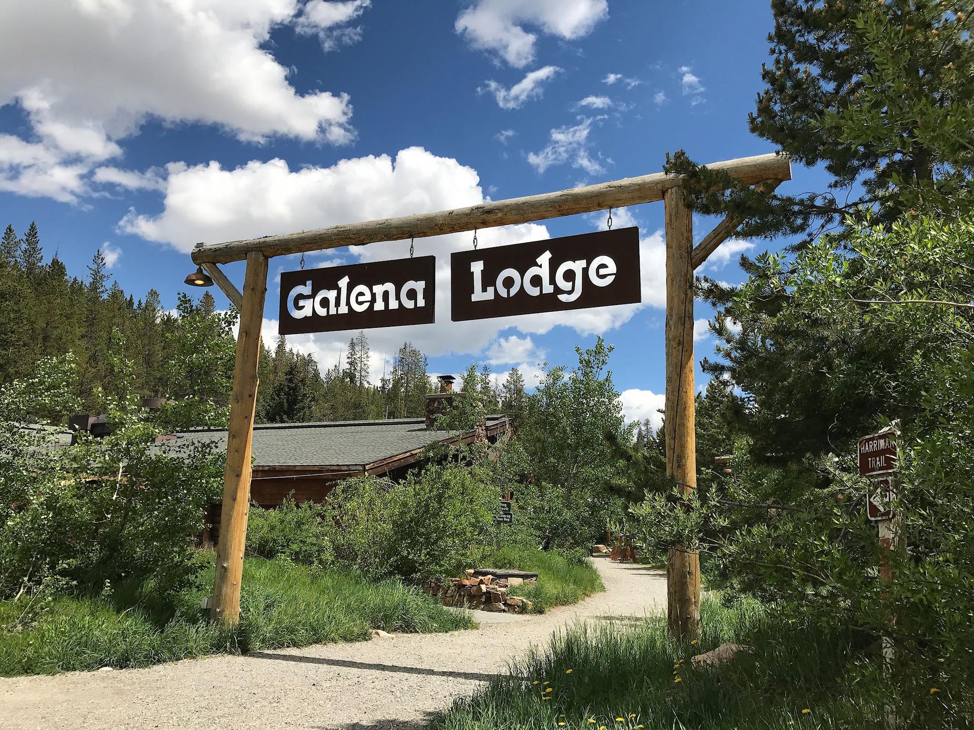 A wooden sign "Galena Lodge" hangs over a path leading to a building.