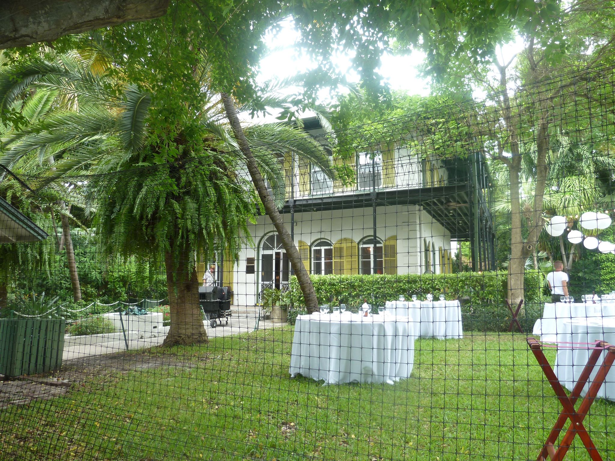 A grand house surrounded by lush tropical trees and outdoor event tables. - St. Pauls Episcopal Church – Duval Street loop from Key West