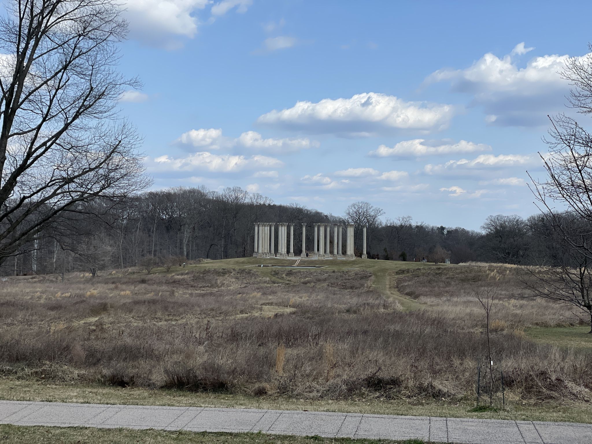 Distant stone columns stand on a hill in a dry, grassy landscape. - National Arboretum: East Side