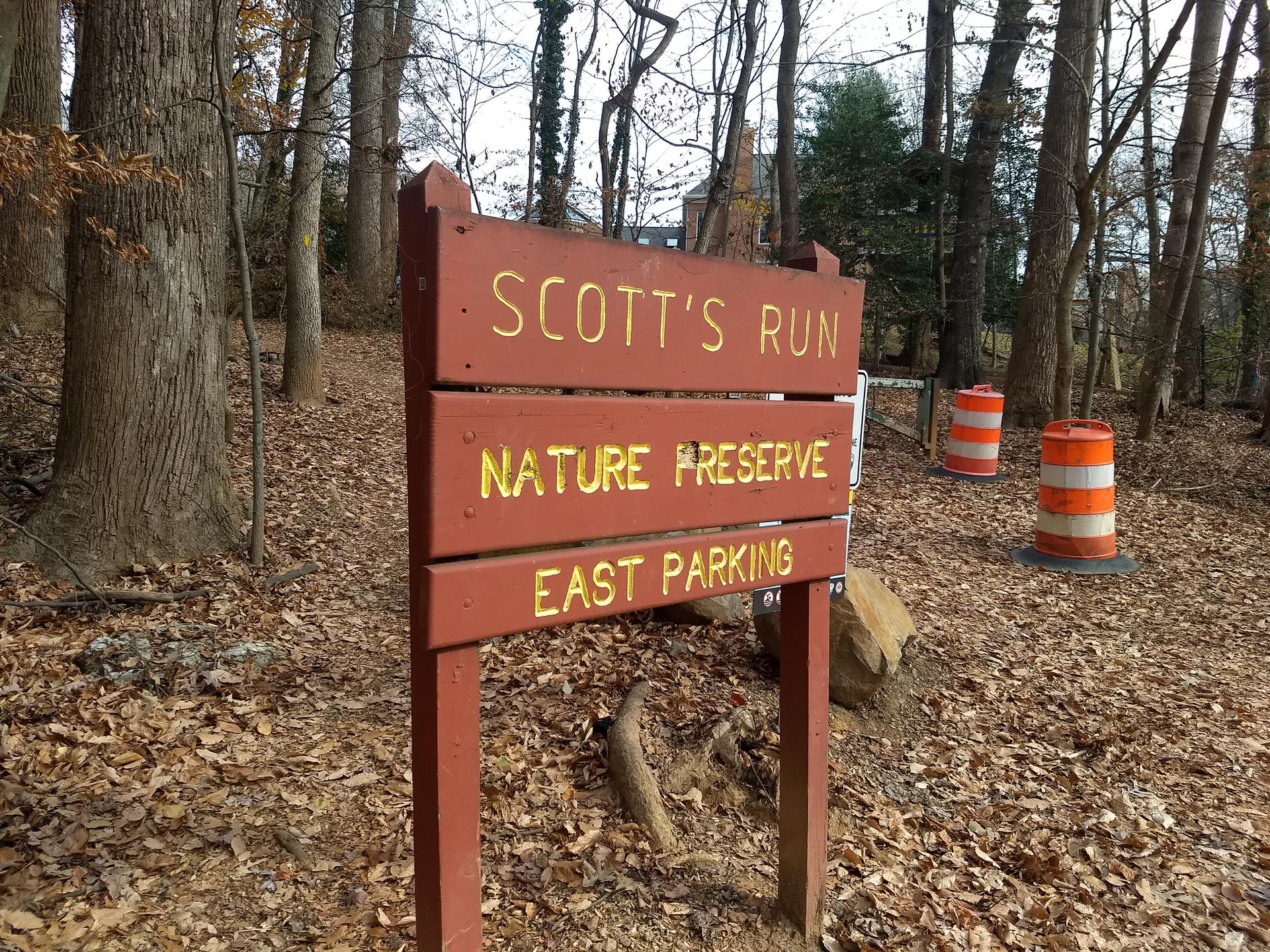 Wooden sign in a forest, "SCOTT'S RUN NATURE PRESERVE EAST PARKING".