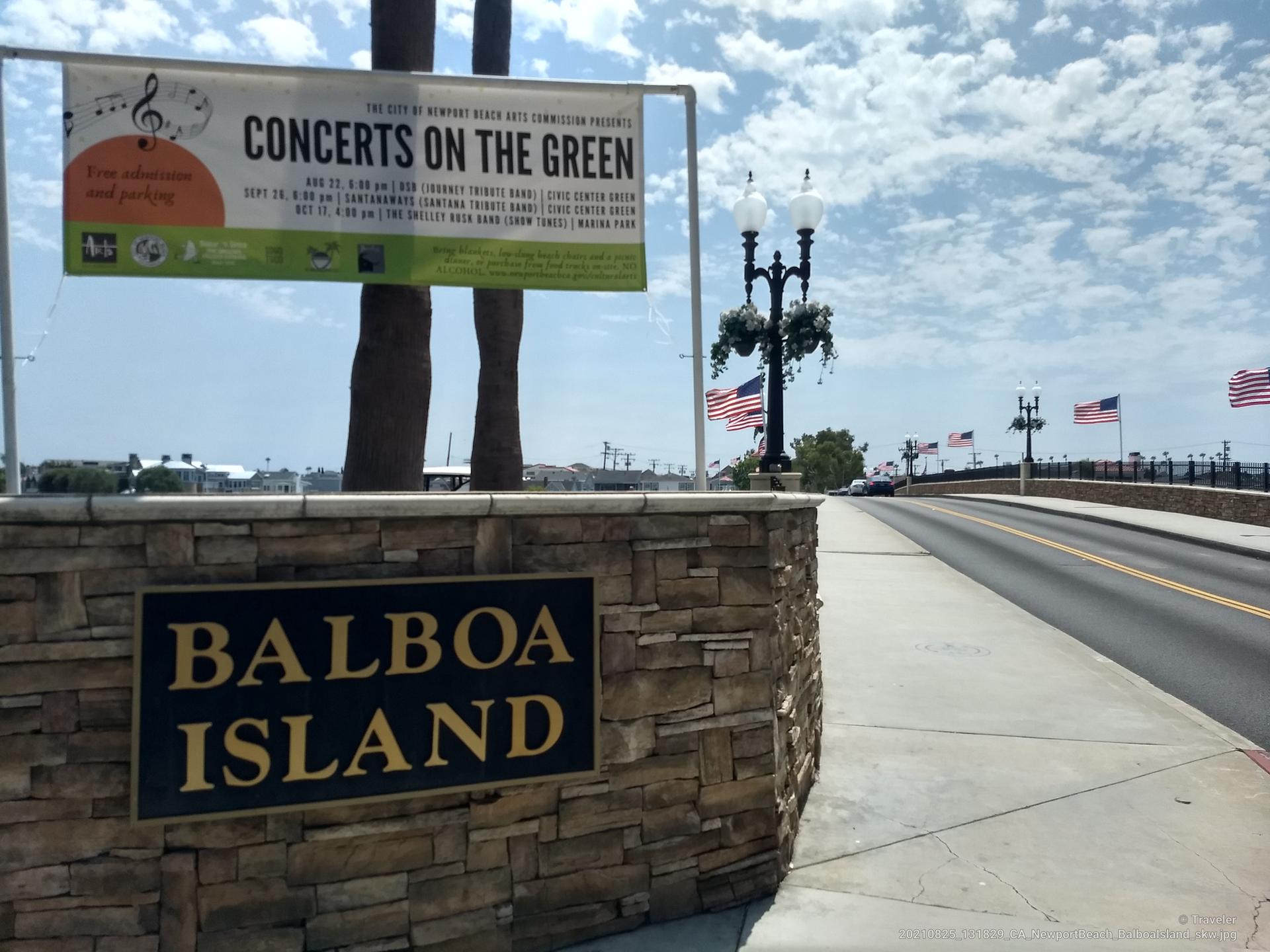 Roadside sign for 'Concerts on the Green' and 'Balboa Island' under cloudy sky.