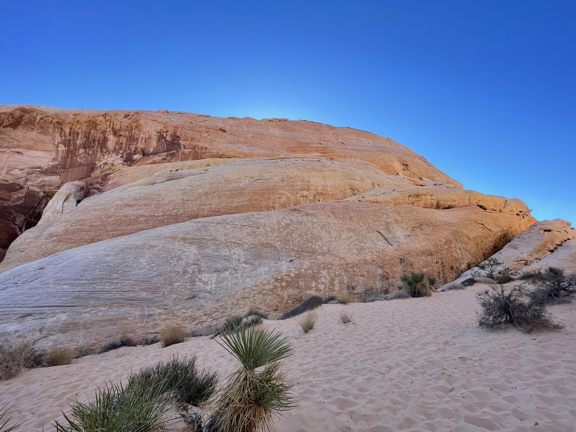 Layered rock formations in a desert landscape under a clear blue sky.