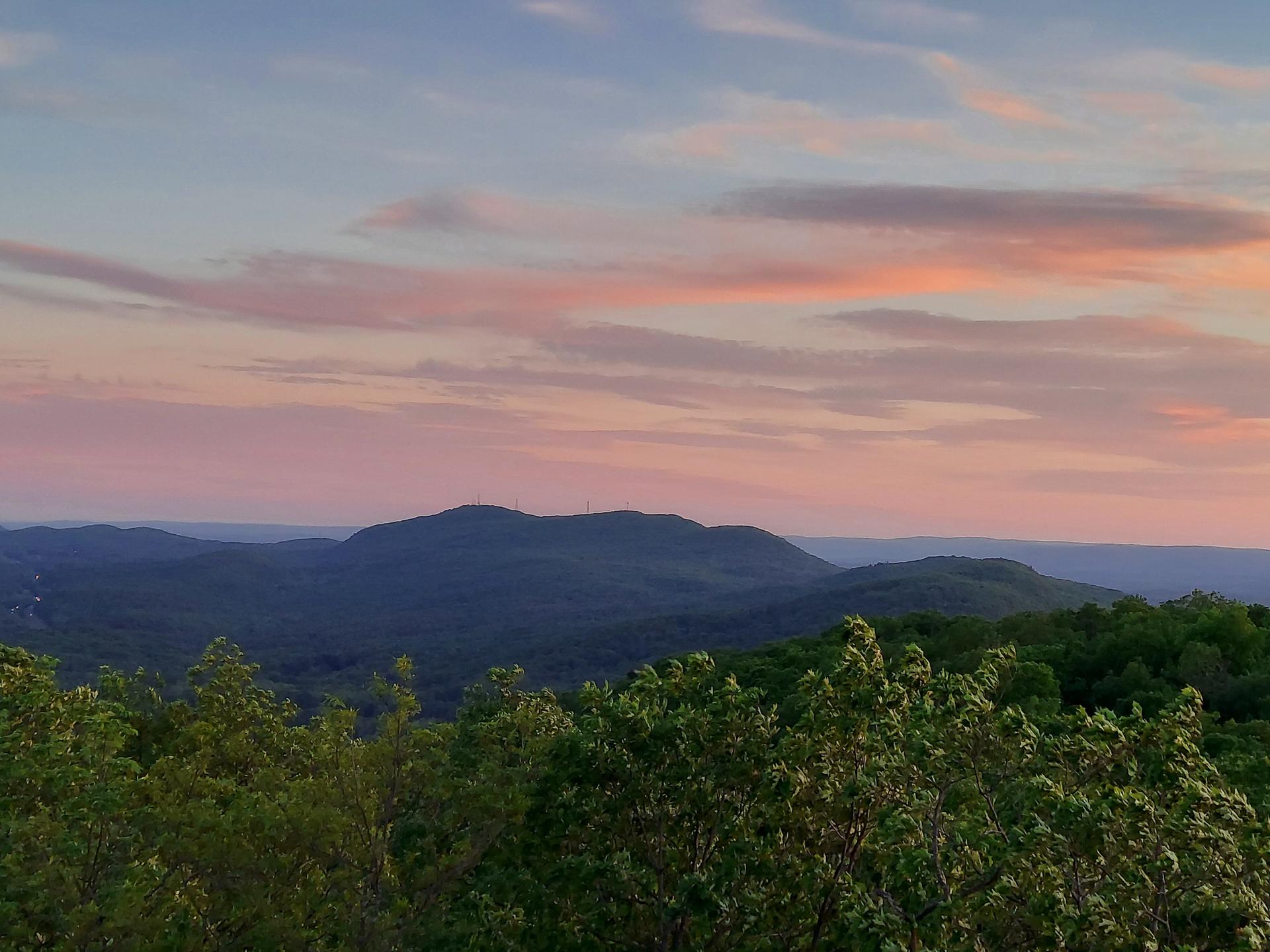 Mountain range at sunset with pink and blue clouds.