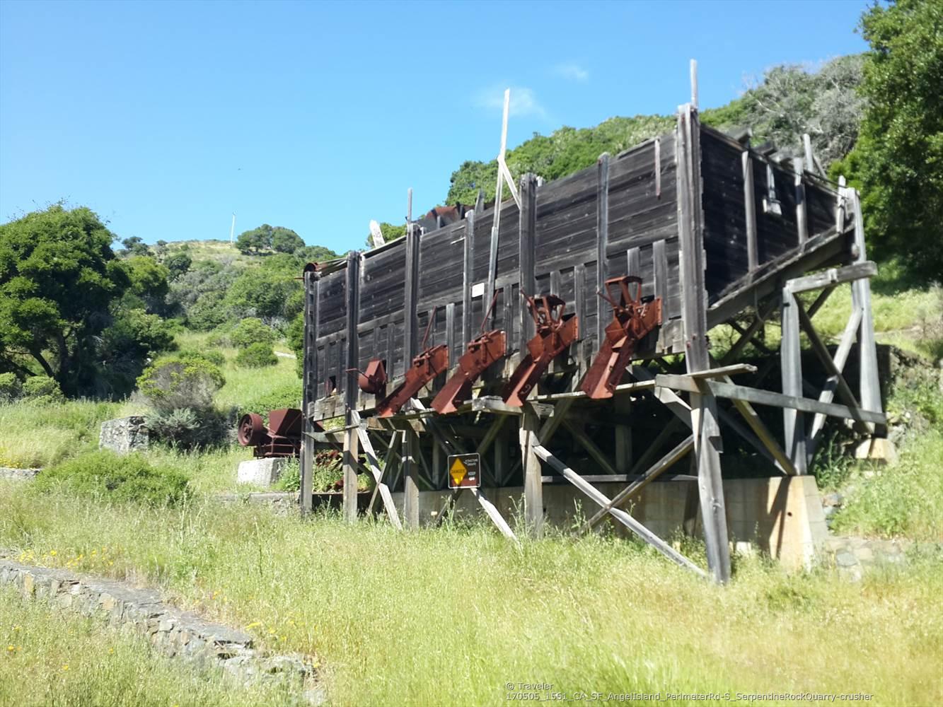 Weathered wooden industrial structure on a grassy hillside under a clear sky.