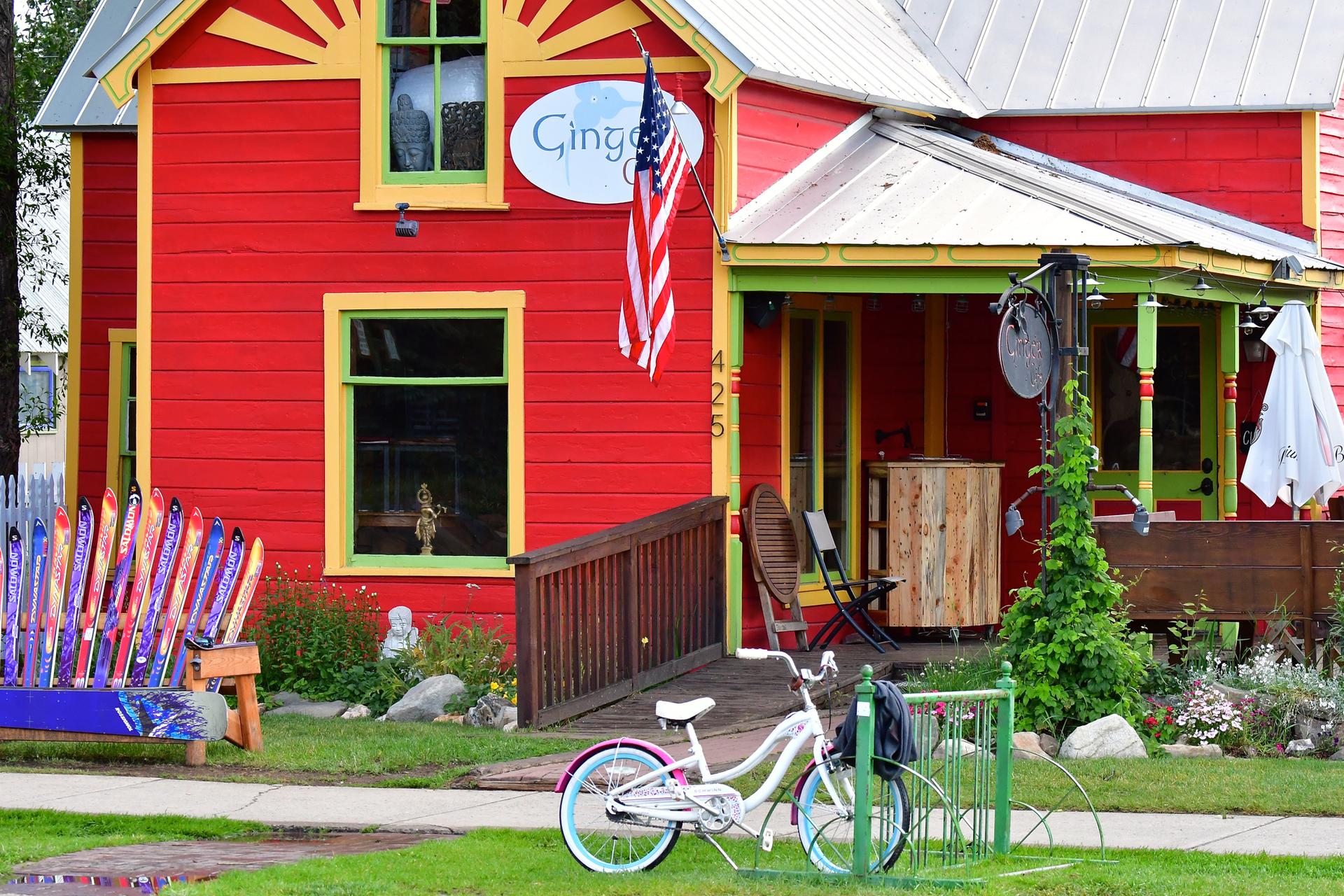 Bright red building with a white bicycle and colorful bench outside.