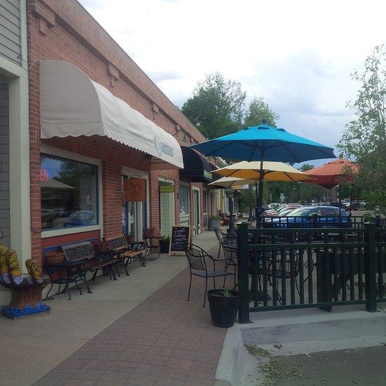 Outdoor patio with colorful umbrellas, tables, and brick buildings.