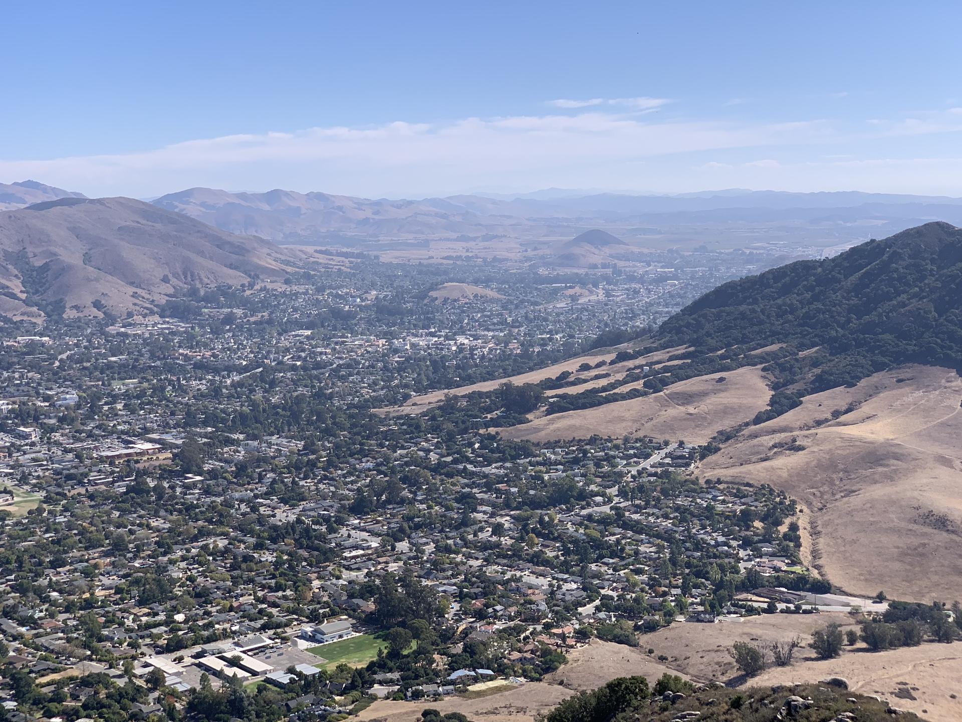 Panoramic view of a town in a valley surrounded by hills on a clear day.
