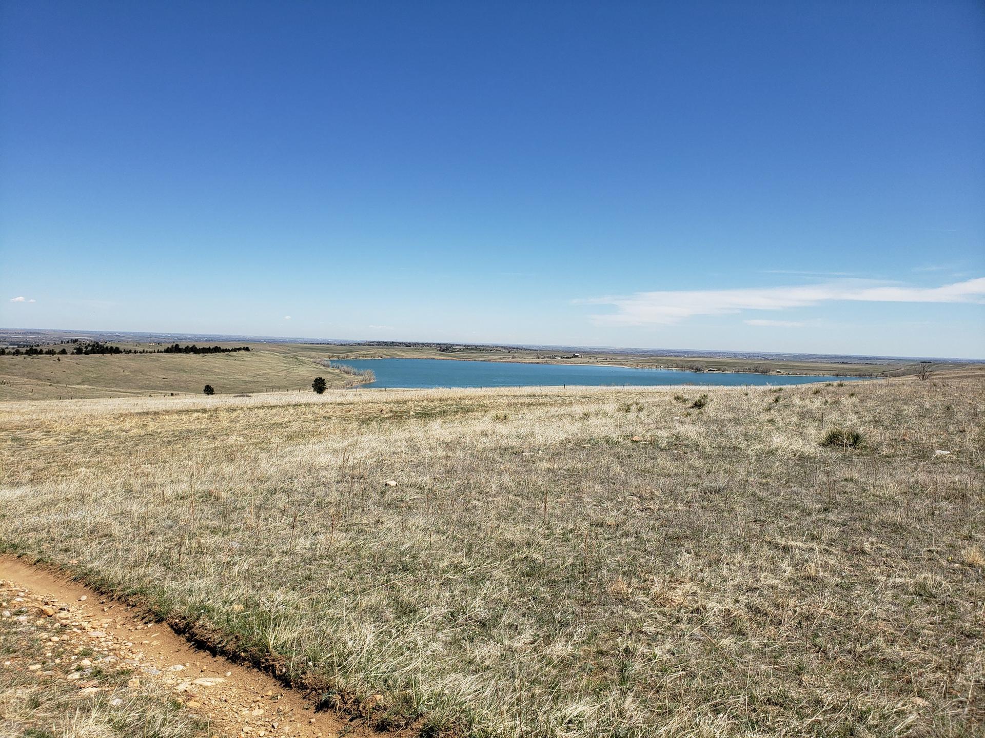 Sunny view of a large lake surrounded by dry, grassy plains.