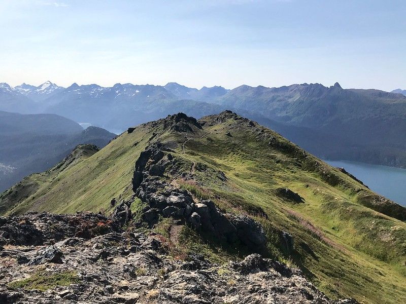 A rocky, grassy mountain ridge under a clear blue sky with distant peaks. - Grace Ridge Trail