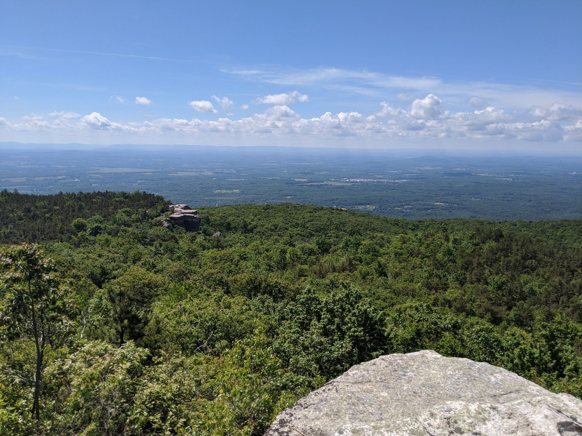 Bright sunny view over a dense green forest and distant hazy landscape. - Castle Point – Lake Minnewaska loop from Route 44/55 Overlook