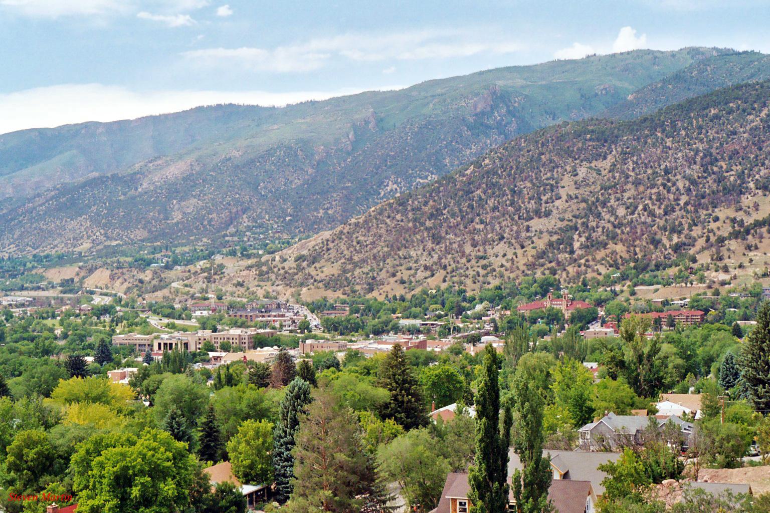 Aerial view of a town surrounded by green, tree-covered mountains.