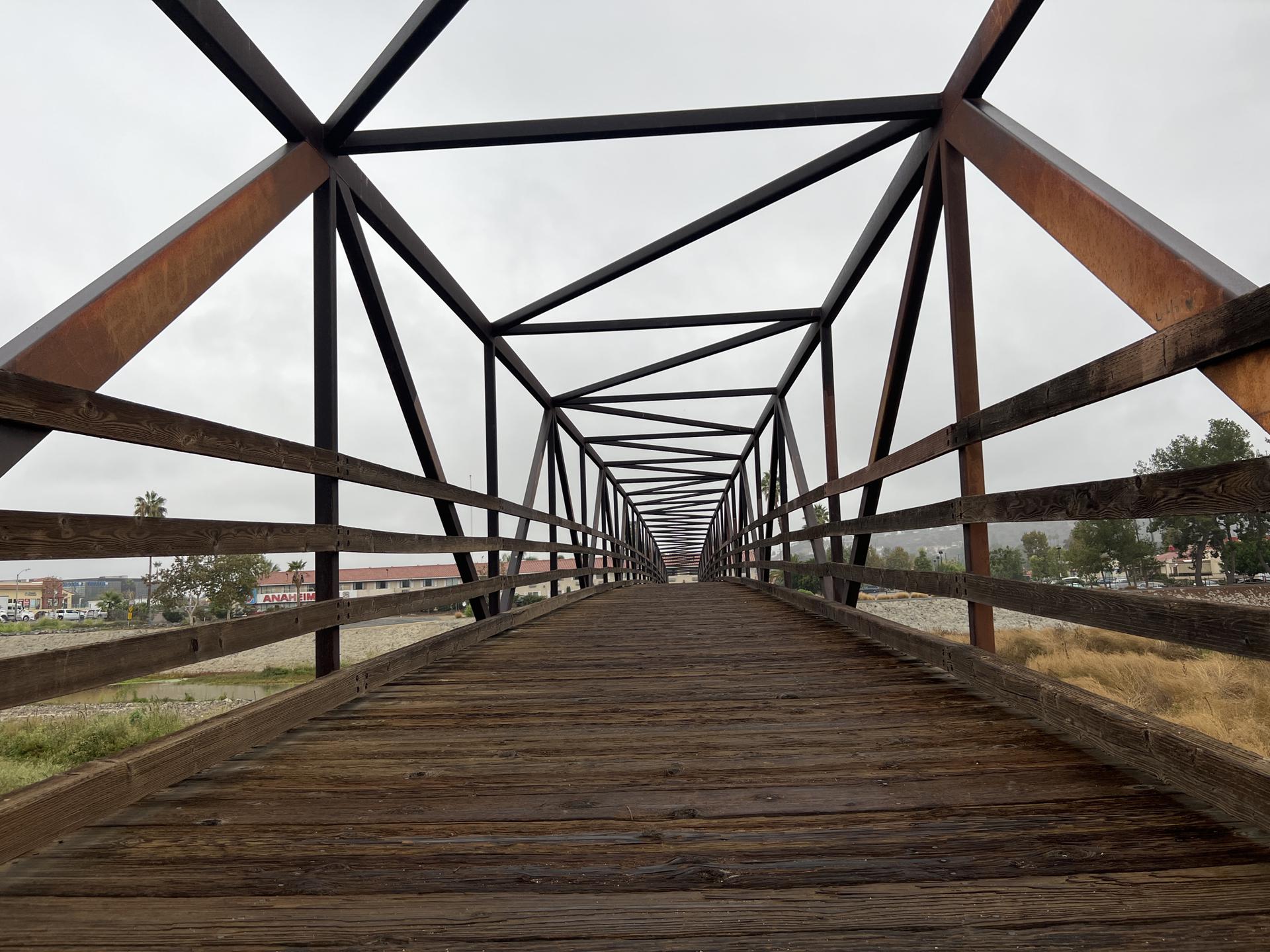 Long wooden and metal truss bridge under an overcast sky.