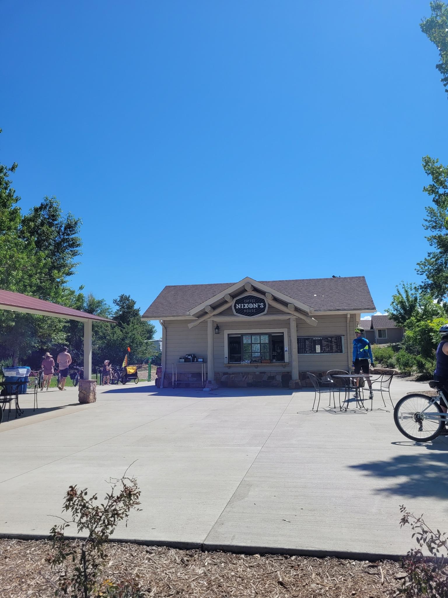 A small building with outdoor seating and people under a clear blue sky.