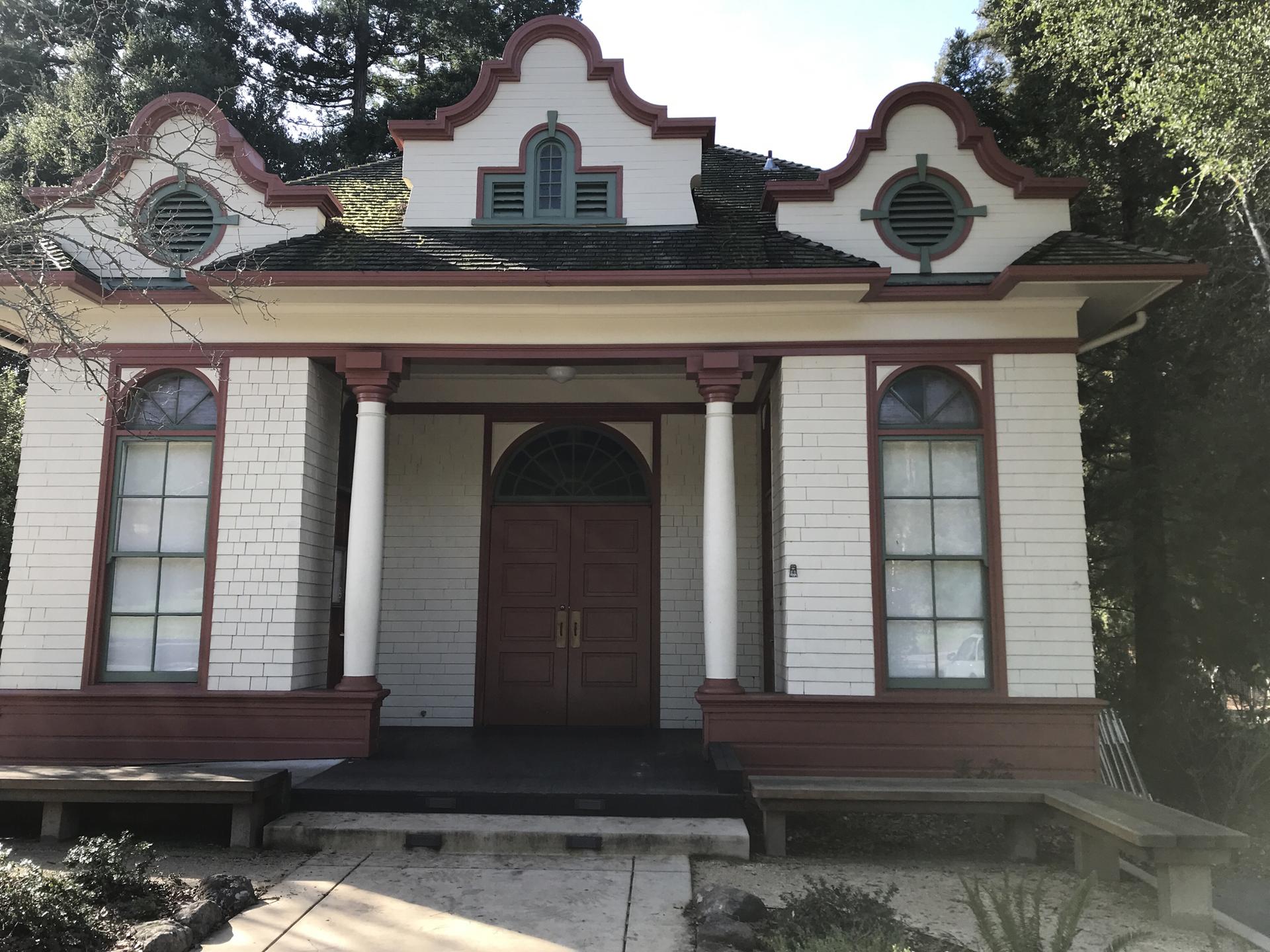 Ornate white and red historic building with columns and arched double doors.