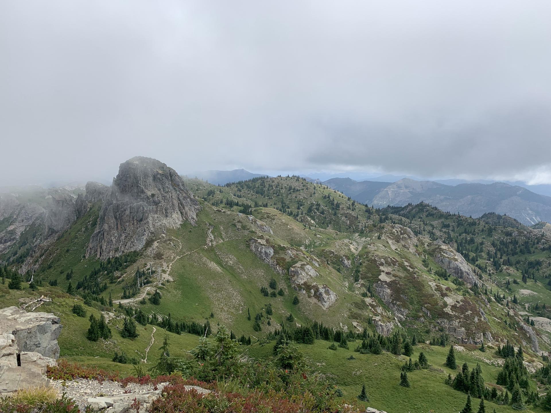 Overcast view of green, rocky mountain ridges and valleys.