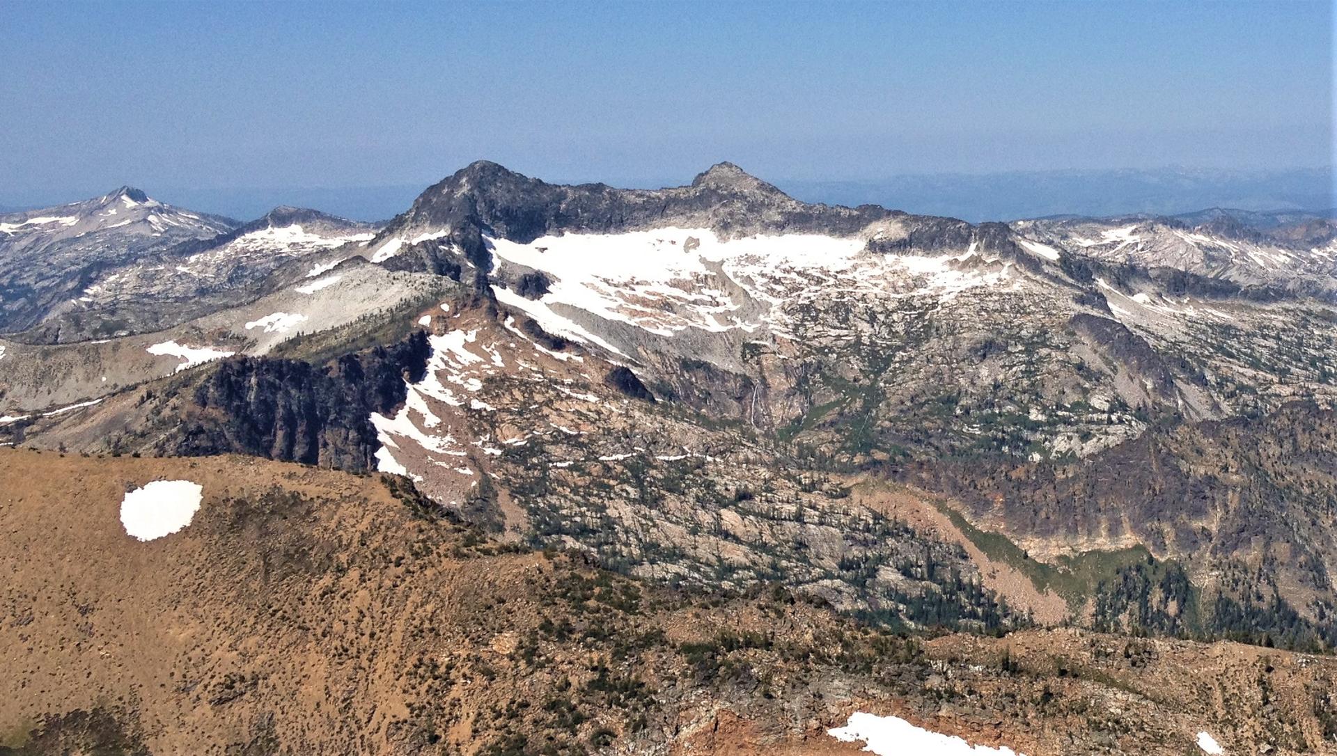 Panoramic view of rugged, snow-capped mountains under a clear blue sky.