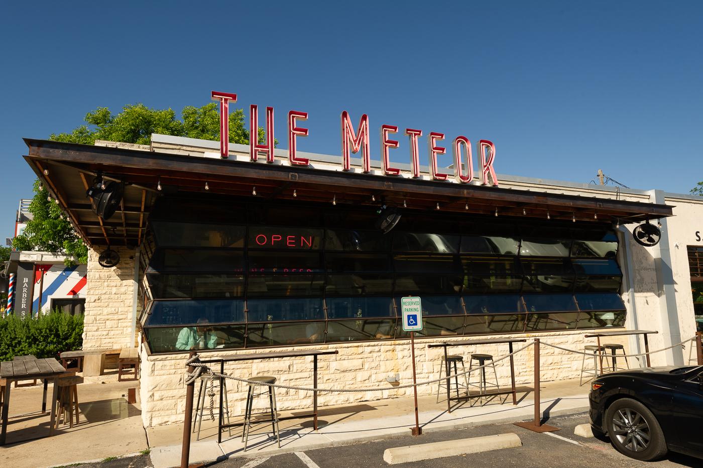Sunny day exterior of a building with a neon "THE METEOR" sign.