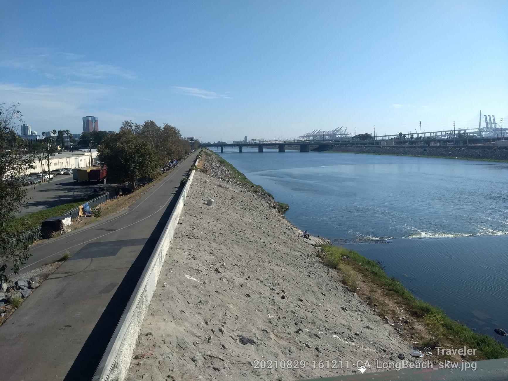 Wide river with distant bridge and city under a clear blue sky.