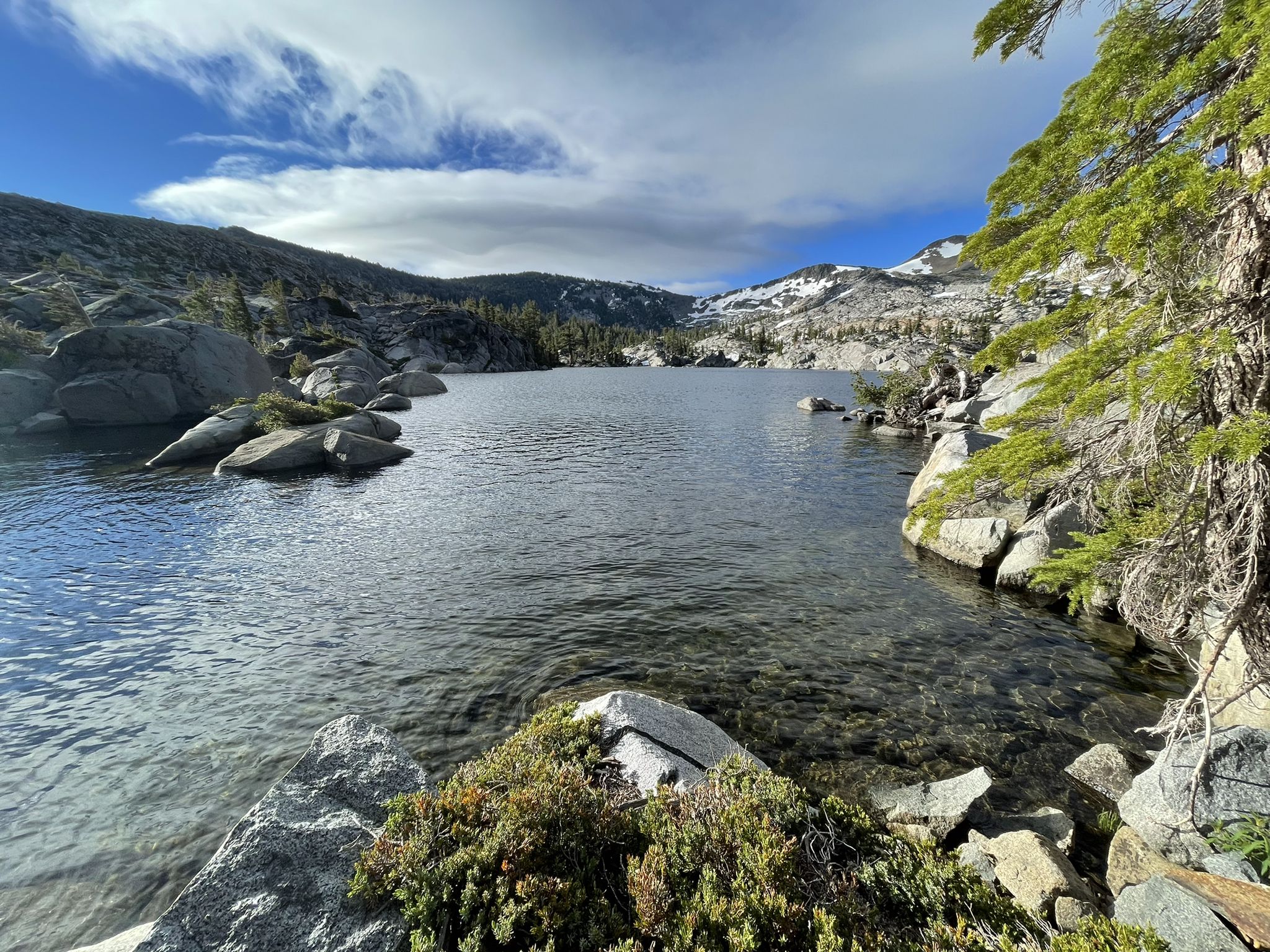 Clear lake with rocky shores, pine trees, and snow-capped mountains. - Eagle Falls Trailhead to Middle Velma, Dicks, and Susie Lake