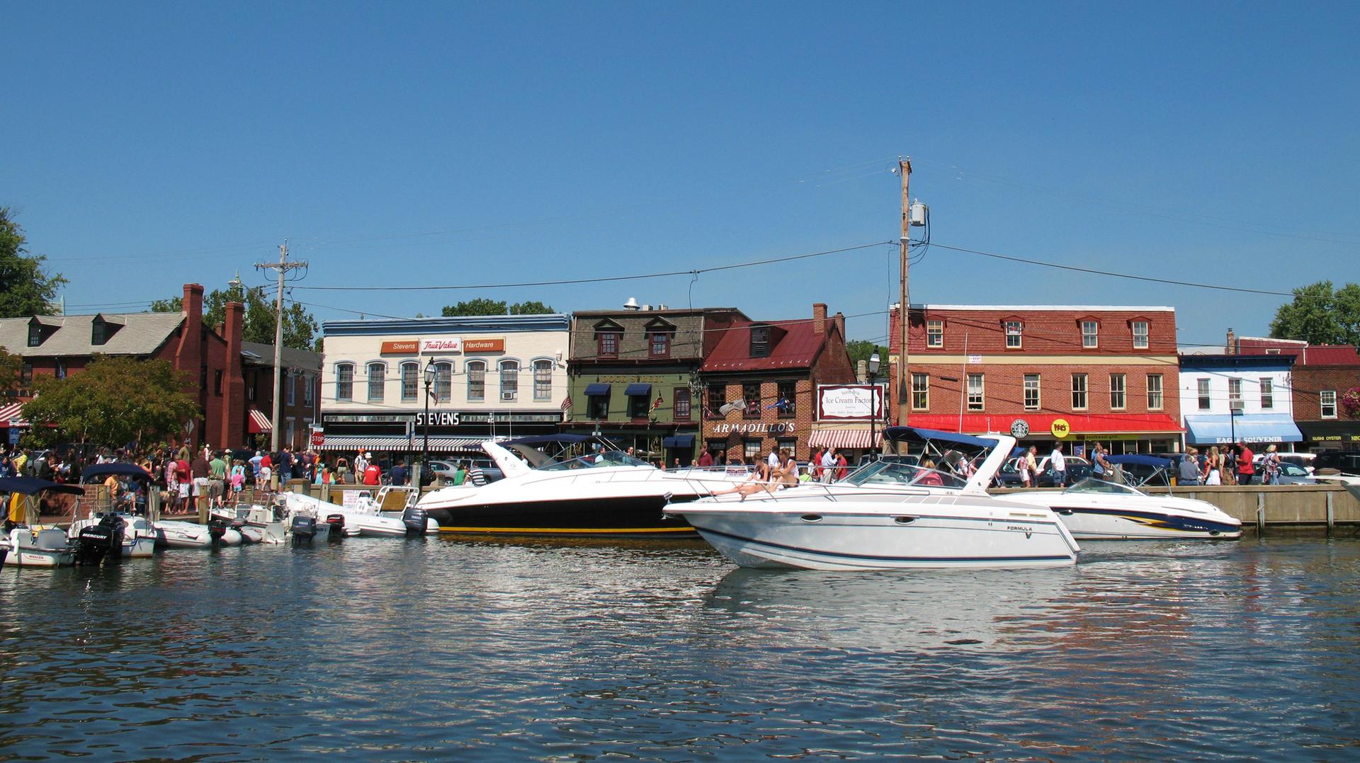 Boats docked in front of historic waterfront buildings with many people.