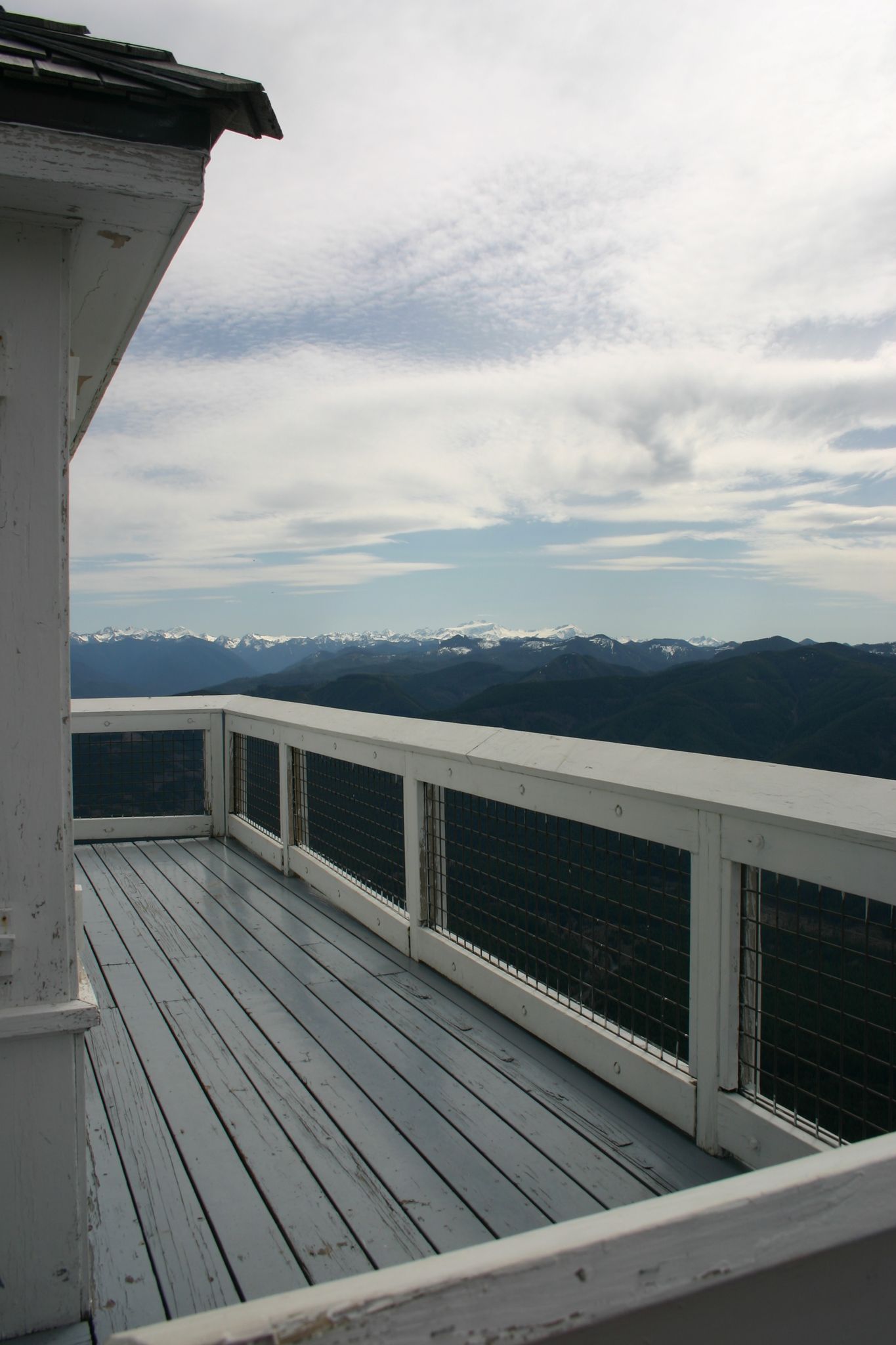Wooden deck of a building overlooking distant mountains under a cloudy sky. - Kloshe Nanitch Trail