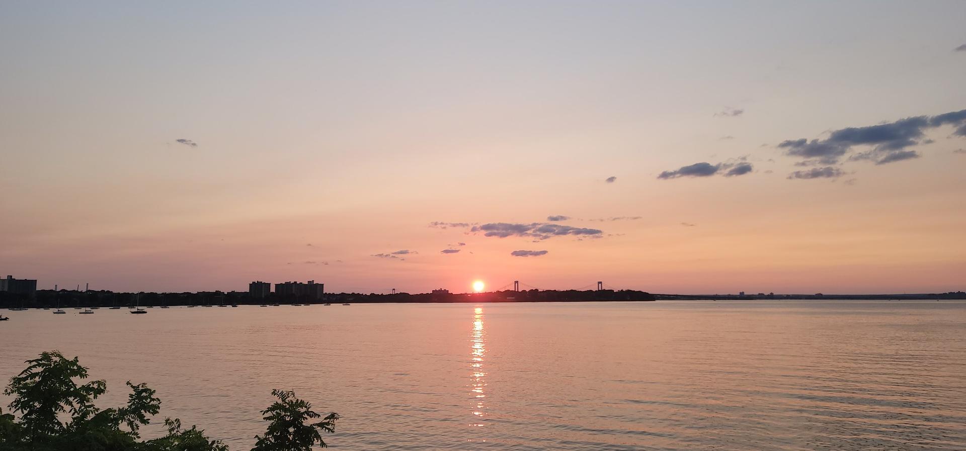 Golden sunset over a wide body of water with a distant city skyline.