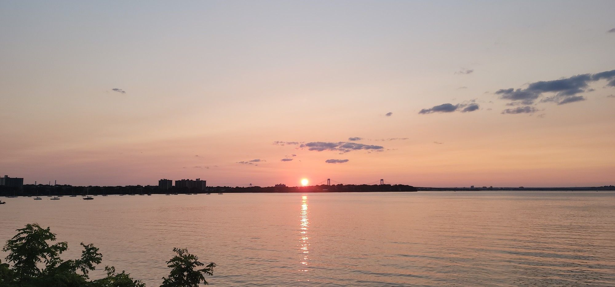 Golden sunset over a wide body of water with a distant city skyline. - 495 Service Road loop