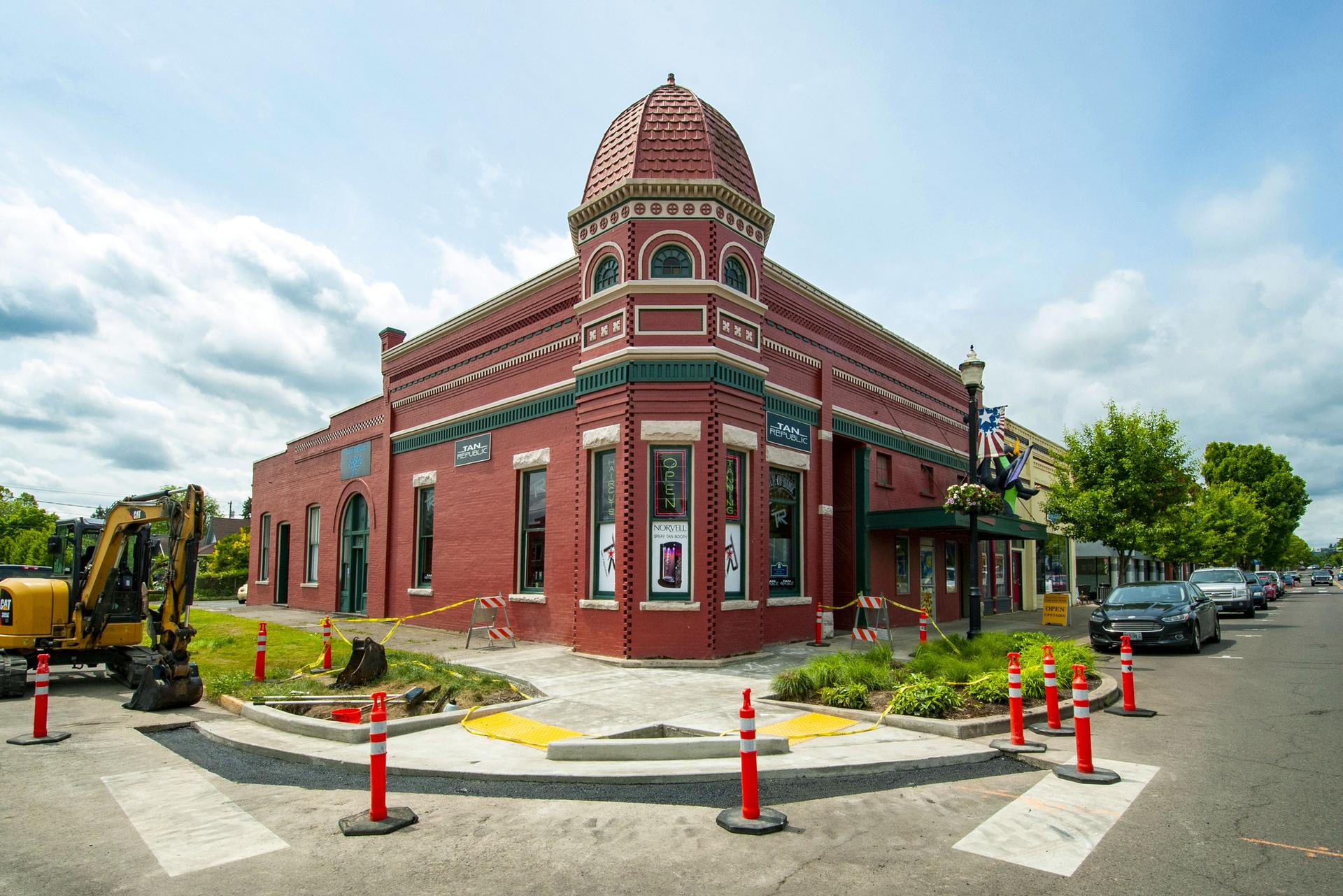 Sunny street corner with a red brick building and construction equipment.