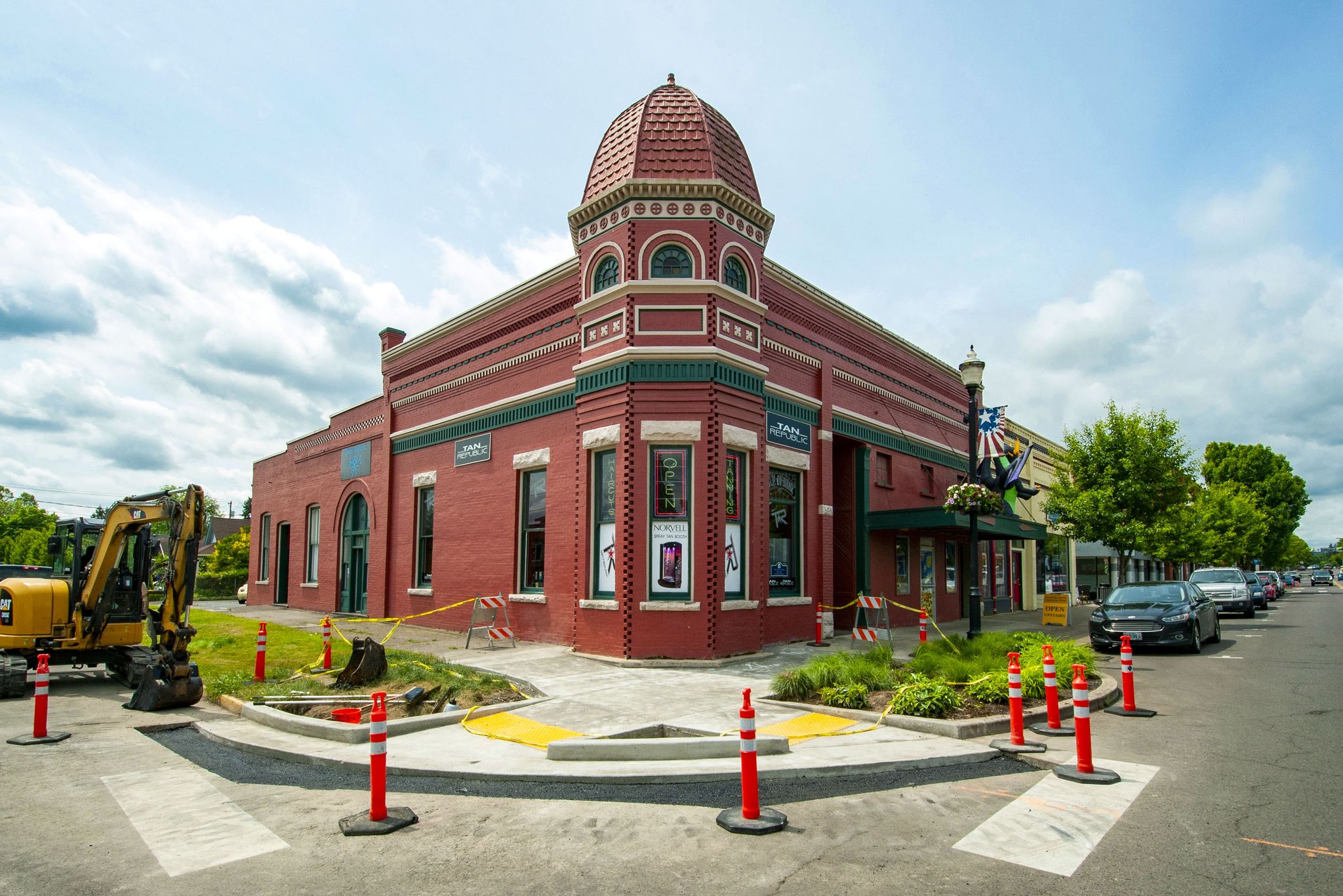Sunny street corner with a red brick building and construction equipment. - Western Valley Bikeway