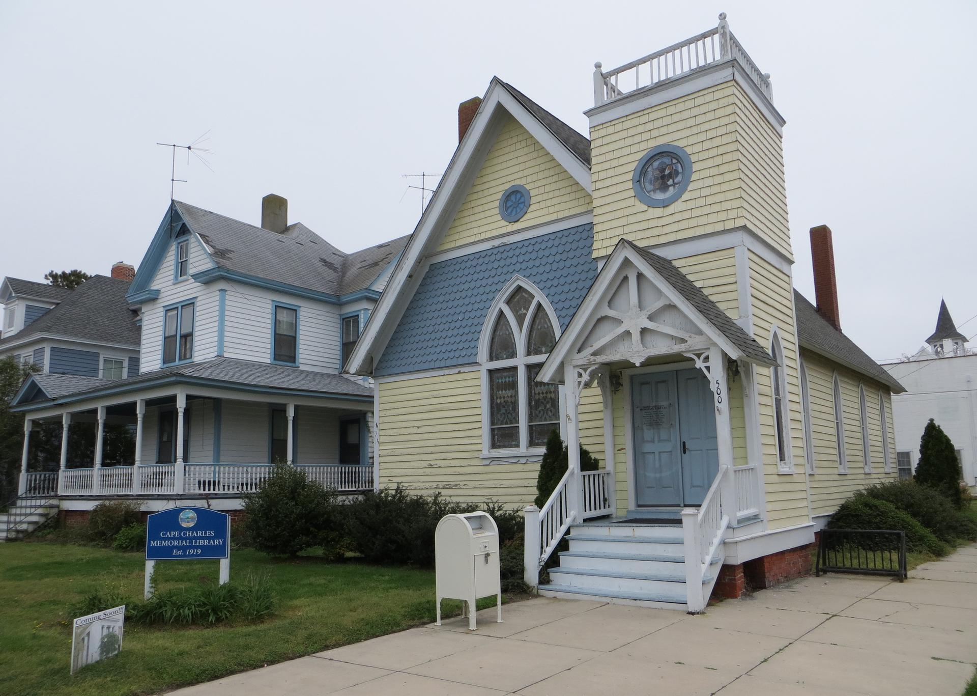 Yellow and blue church building with a steeple and porch on an overcast day.