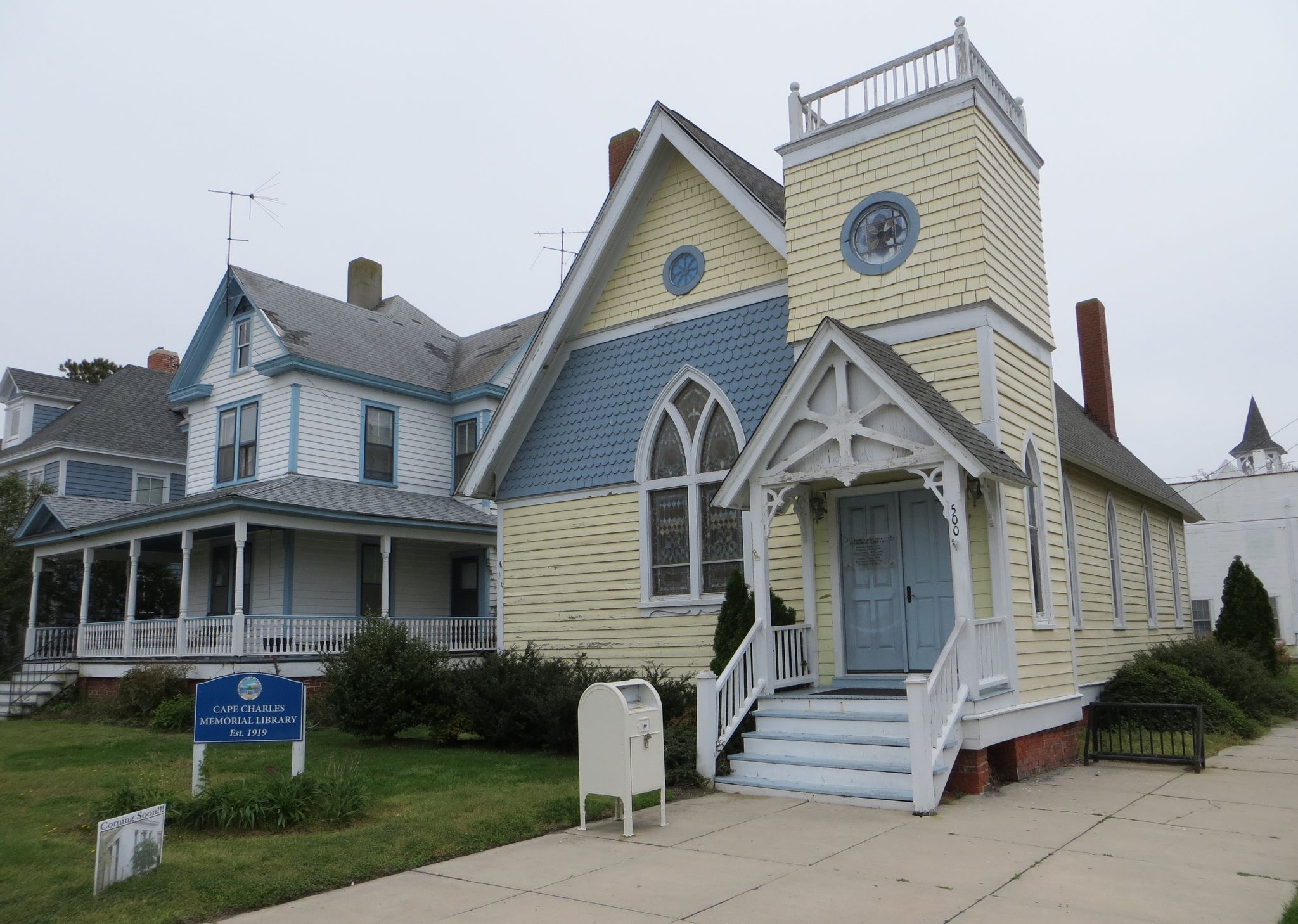 Yellow and blue church building with a steeple and porch on an overcast day. - Southern Tip Bike & Hike Trail