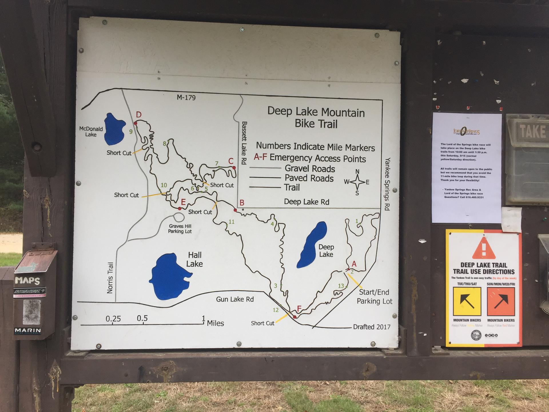 A detailed trail map displayed on a wooden information board outdoors.