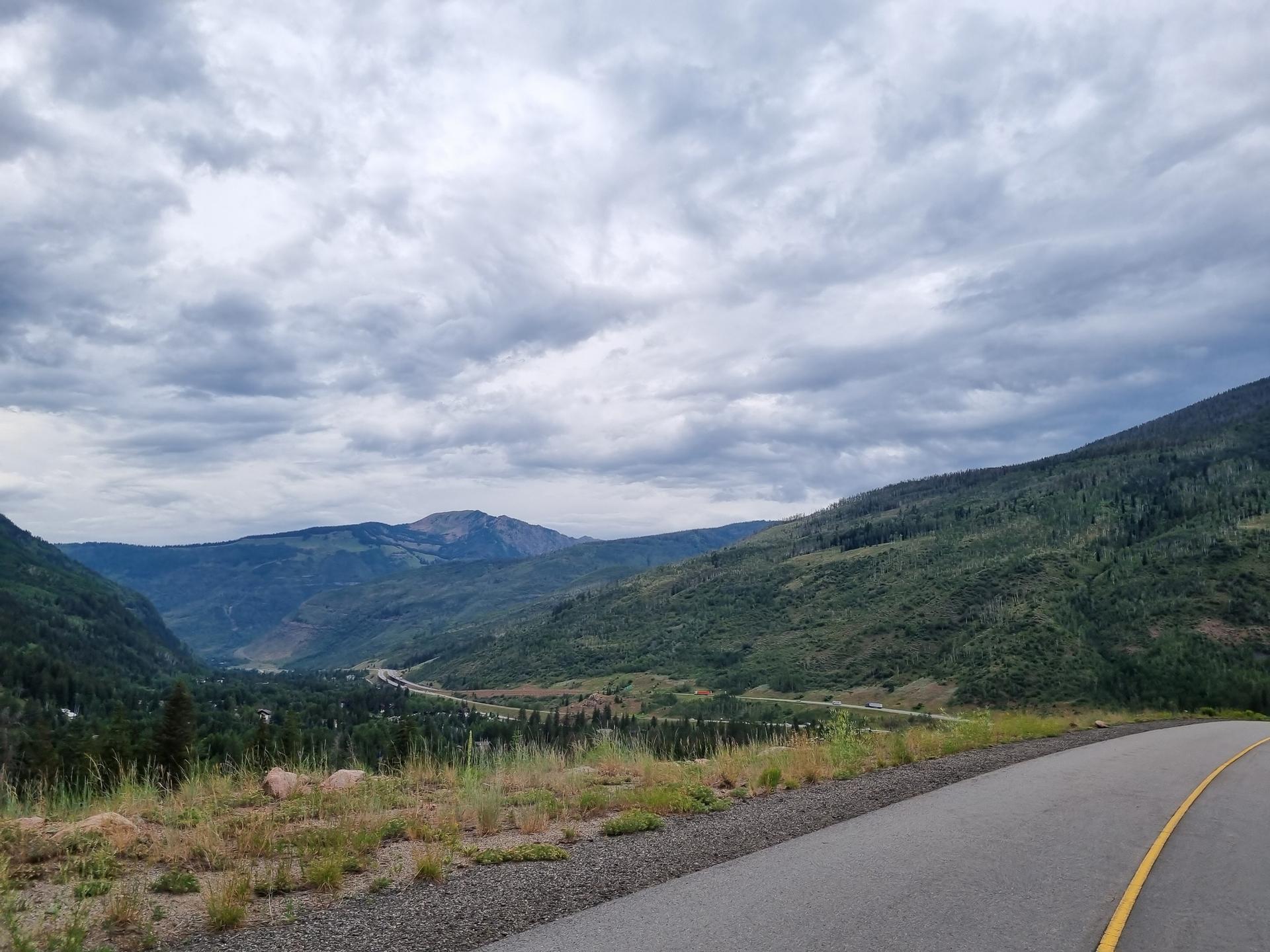 Overcast sky above a winding road through a green mountain valley.