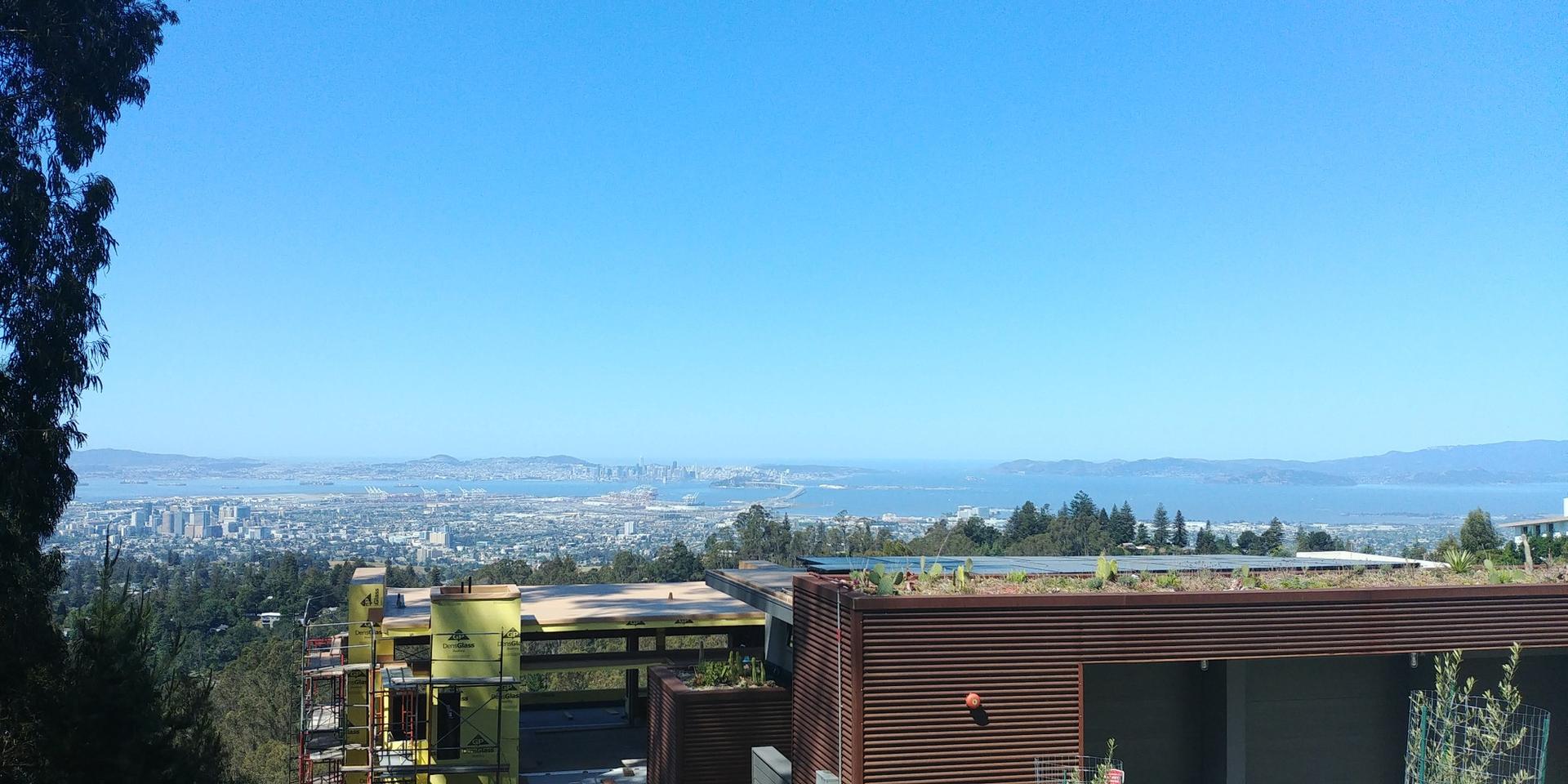 Panoramic view of a city and bay from a hillside with modern buildings.