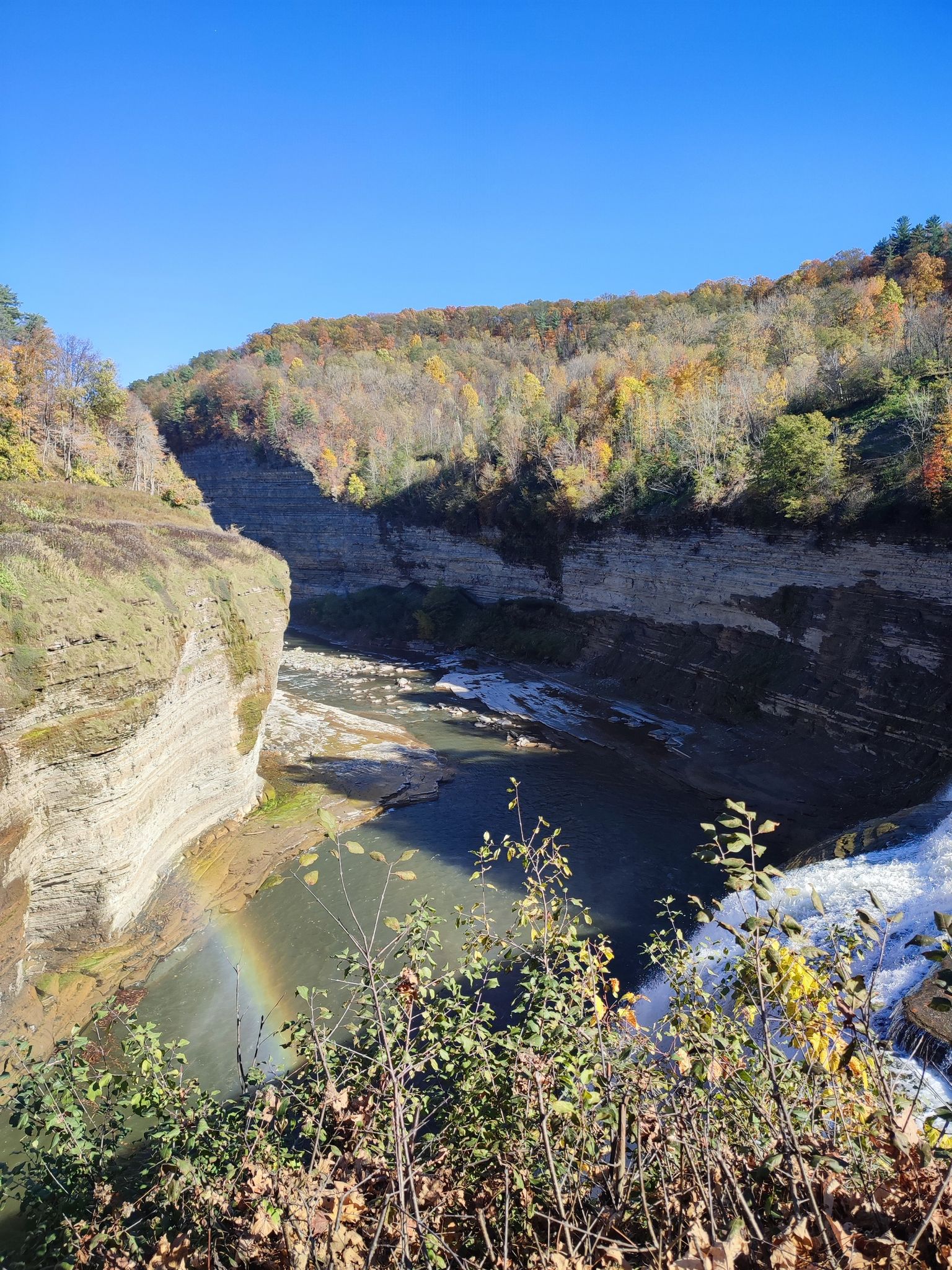 Sunny autumn gorge with a river, colorful trees, and a small rainbow. - Inspiration Point and Lower Falls via Gorge Trail