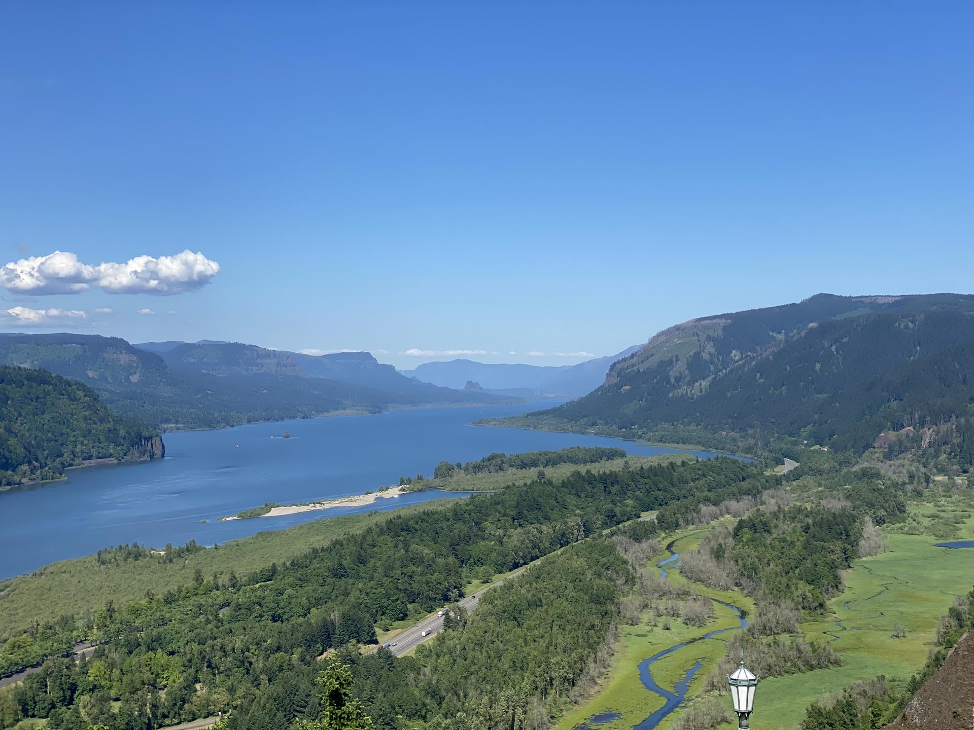 Wide river flowing through a green valley under a clear blue sky.